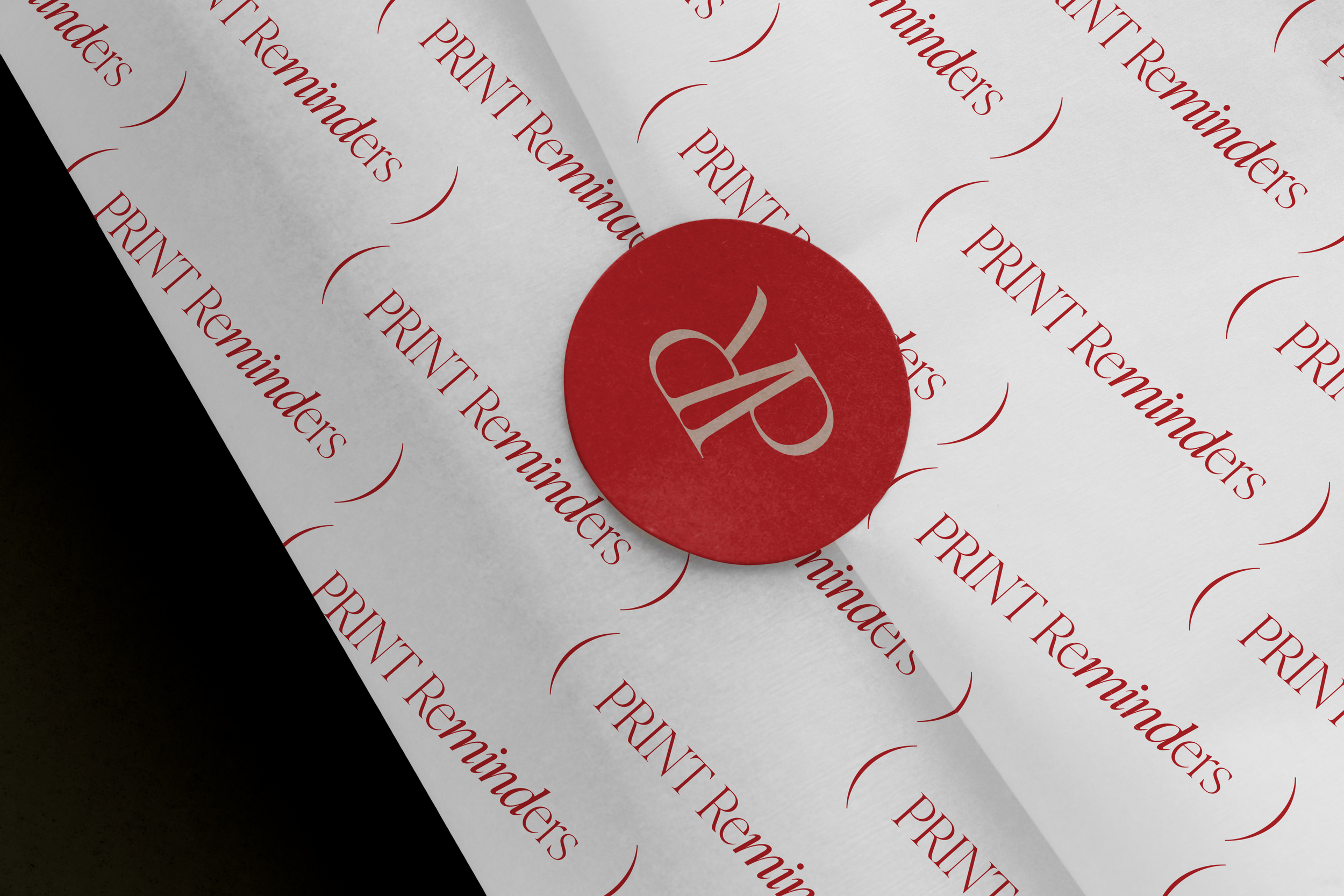 A piece of white paper with red text repeated that says 'PRINTER Reminders' and a red circular sticker with a white stylized 'LP' logo, placed on the paper.