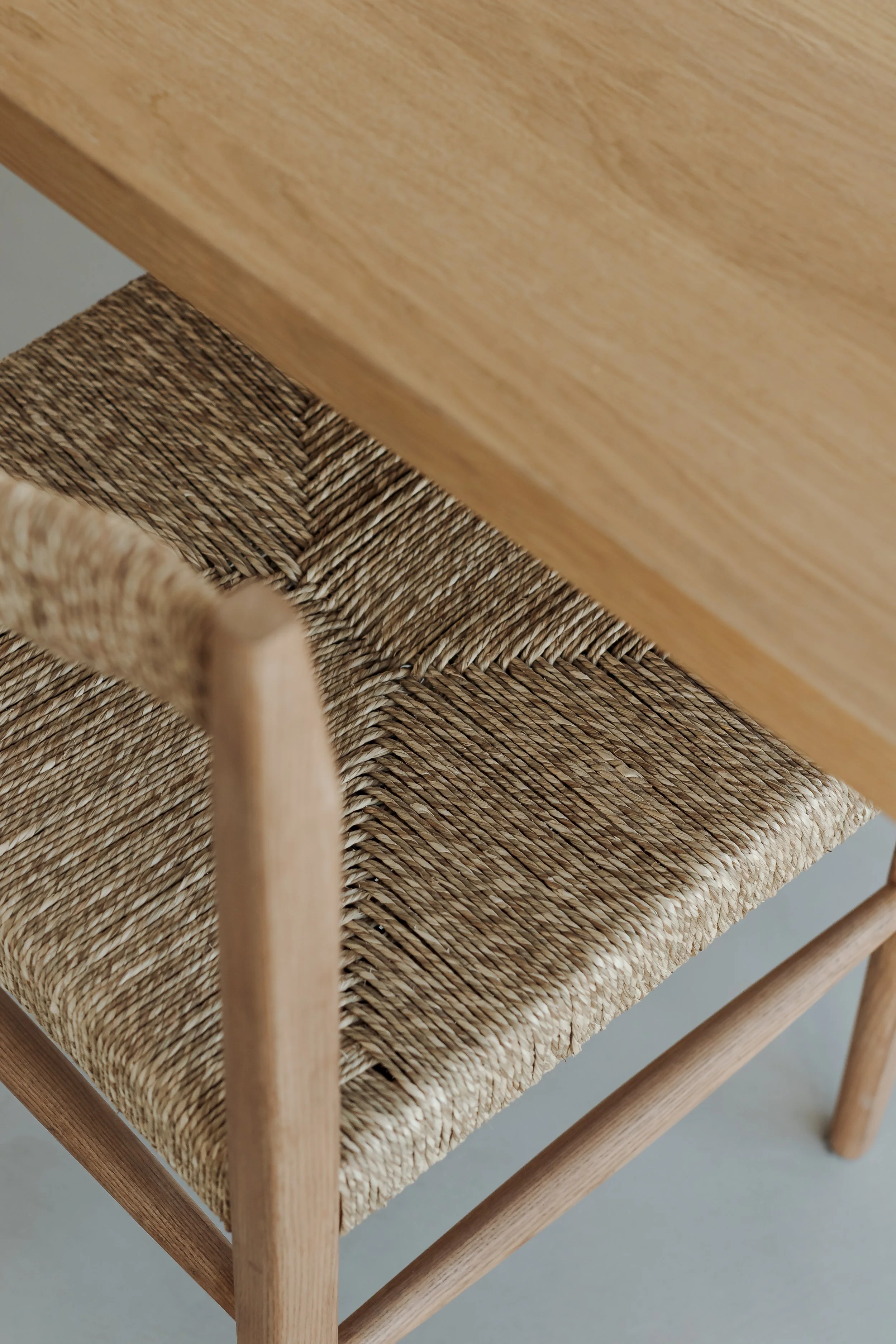 Close-up of a wooden table and a woven rattan chair.