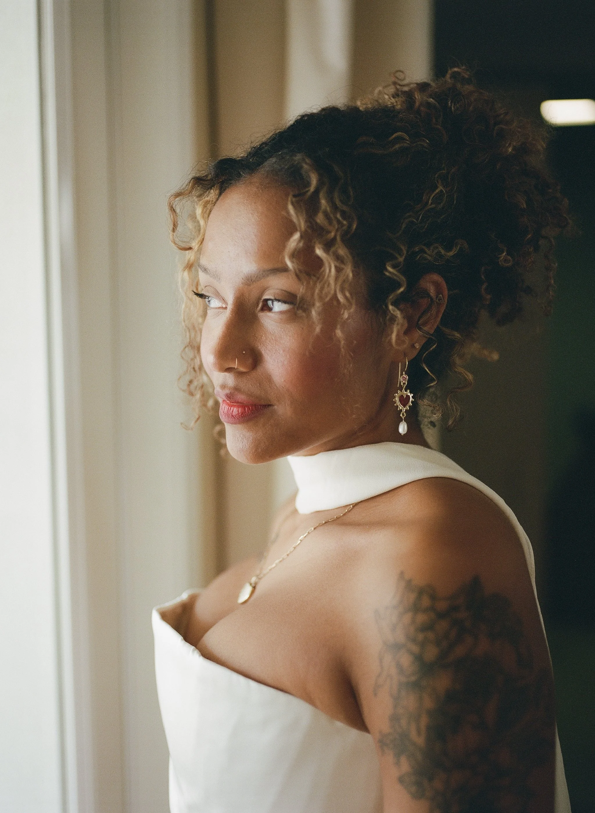 african american bride poses in bridal gown with scarf and soft glam makeup and naturally curly hair styled in an updo