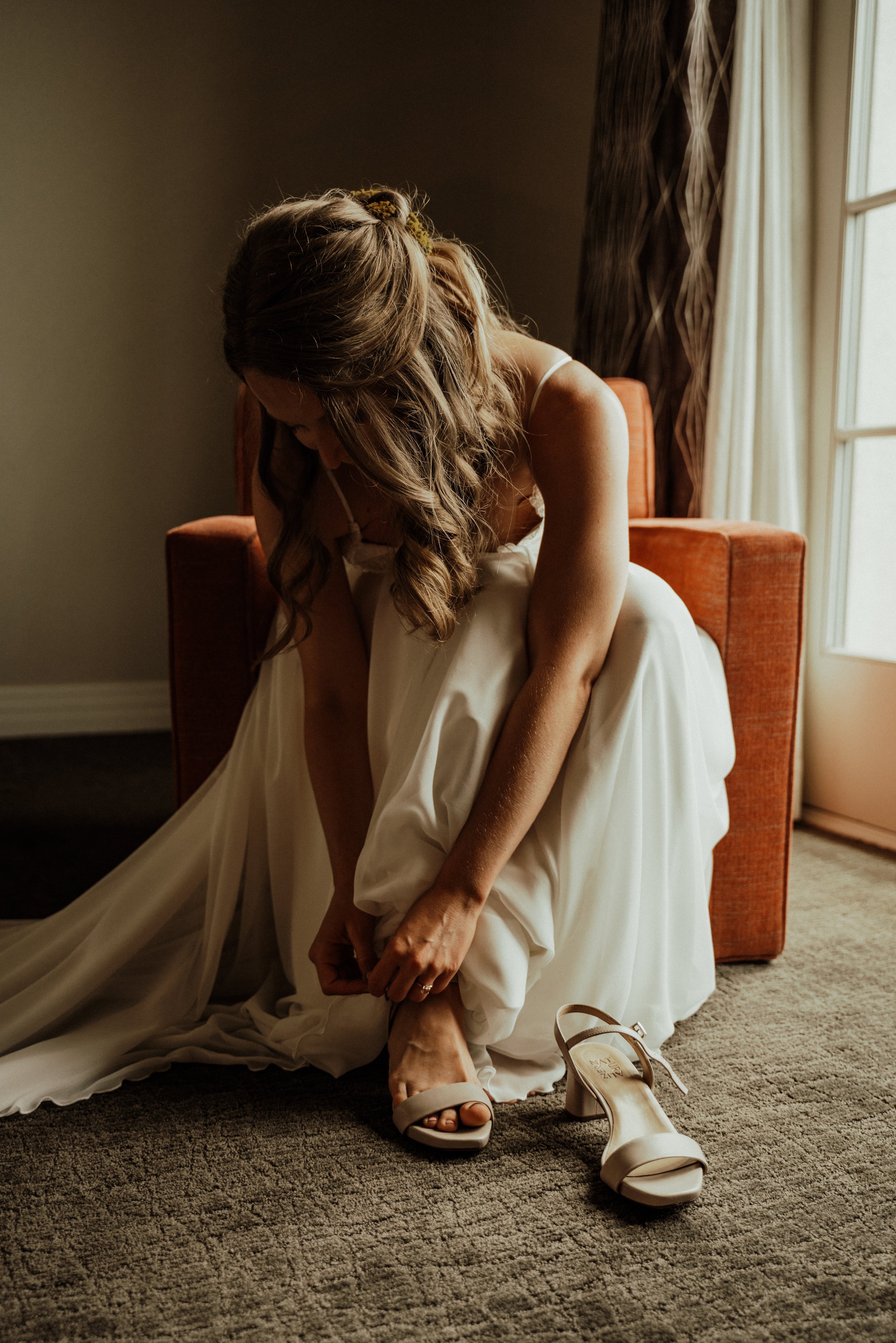 bride putting on her shoes and wedding gown before the ceremony