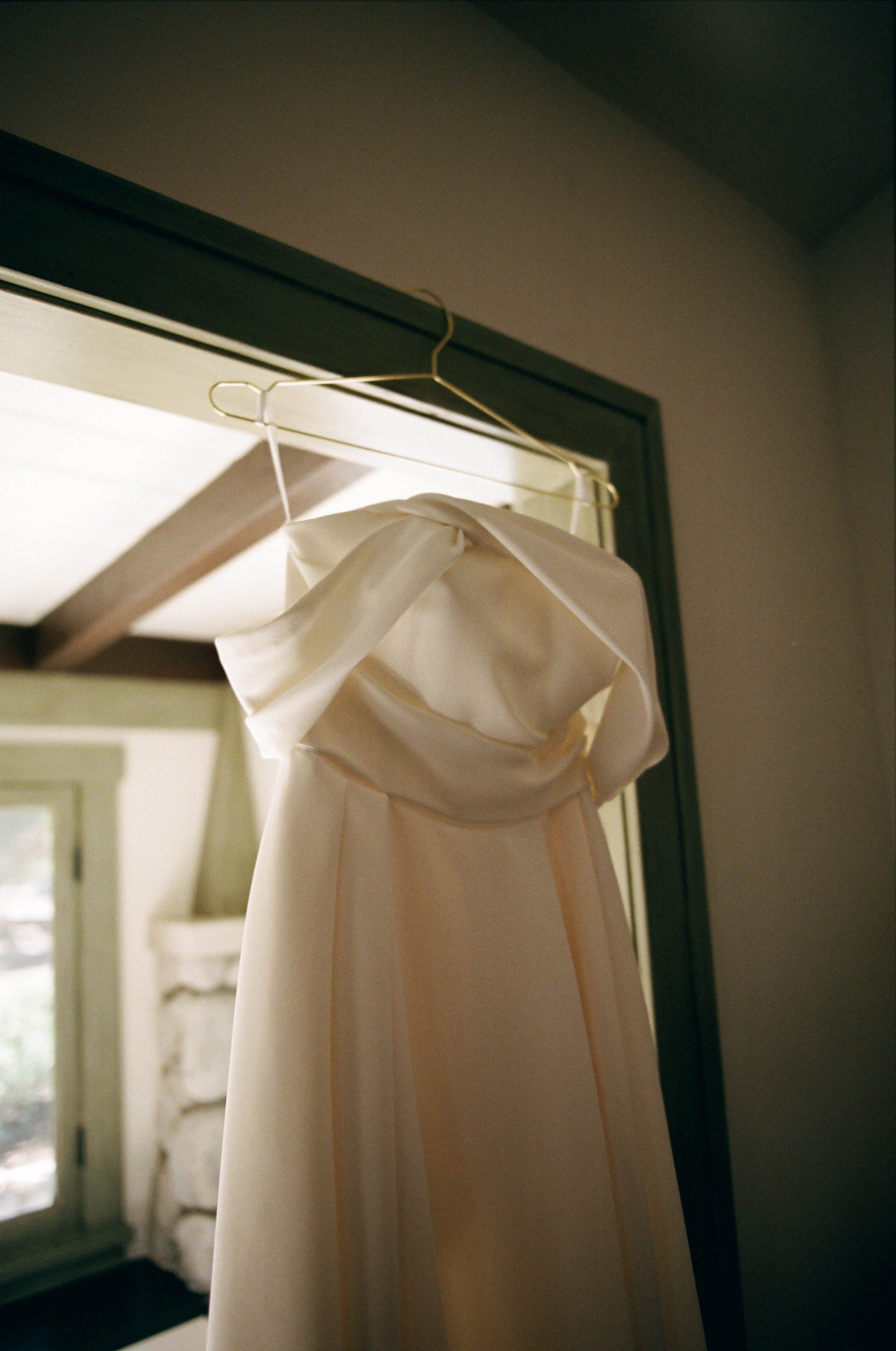 los angeles bride's wedding dress hangs by the window