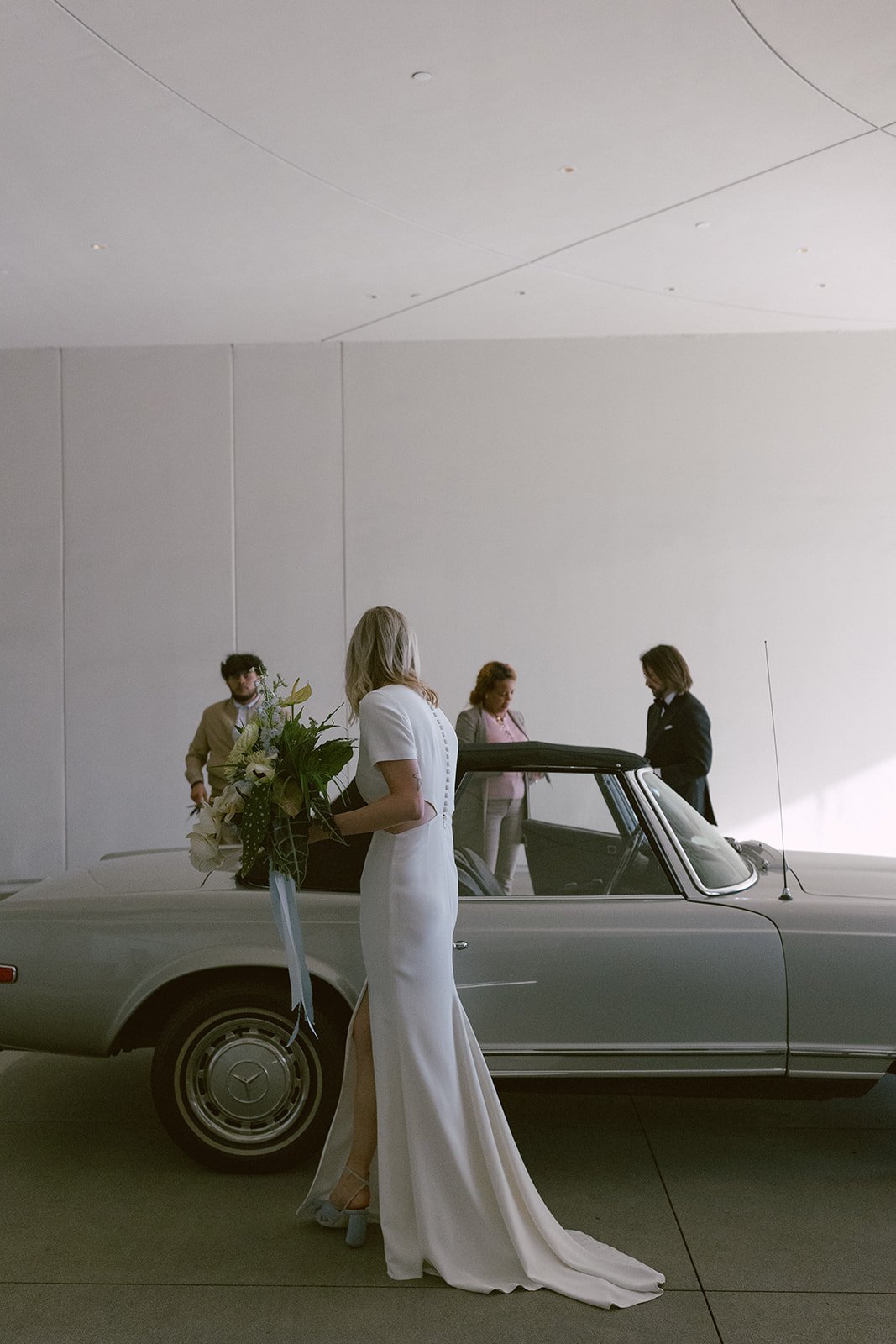bride gets into convertible on the wedding day
