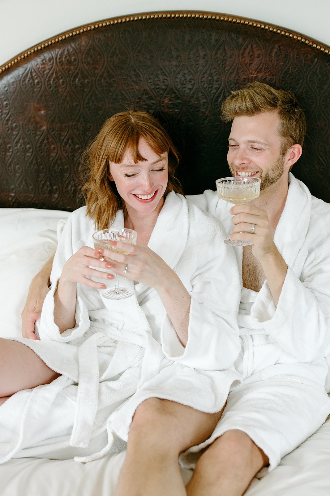 bride and groom wear robes and lounge in bed the morning of their elopement in downtown LA