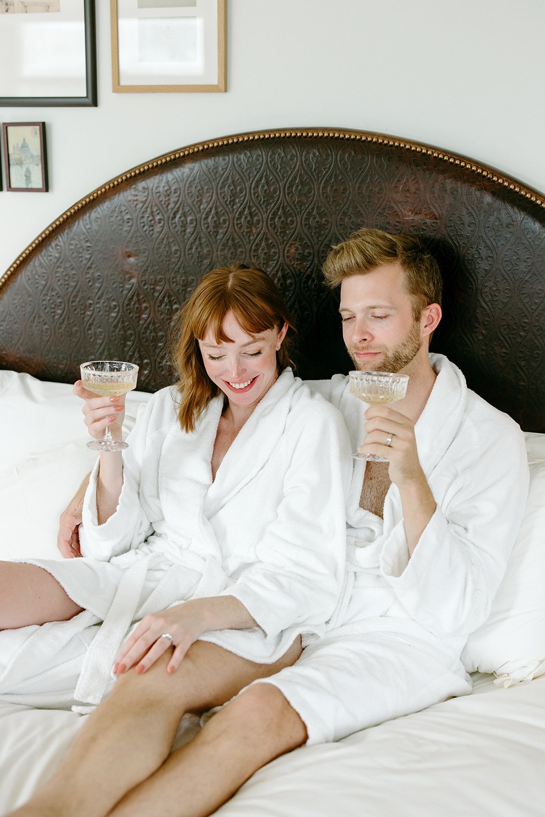 bride and groom wear robes and lounge in bed the morning of their wedding