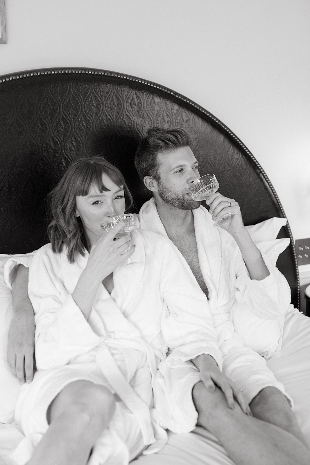 LA bride and groom wear robes and lounge in bed before their wedding