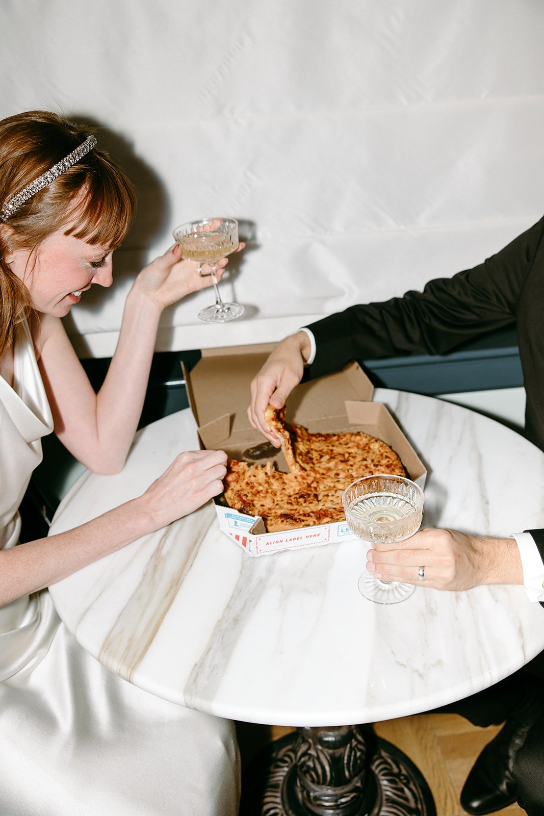 bride and groom eat pizza and cake