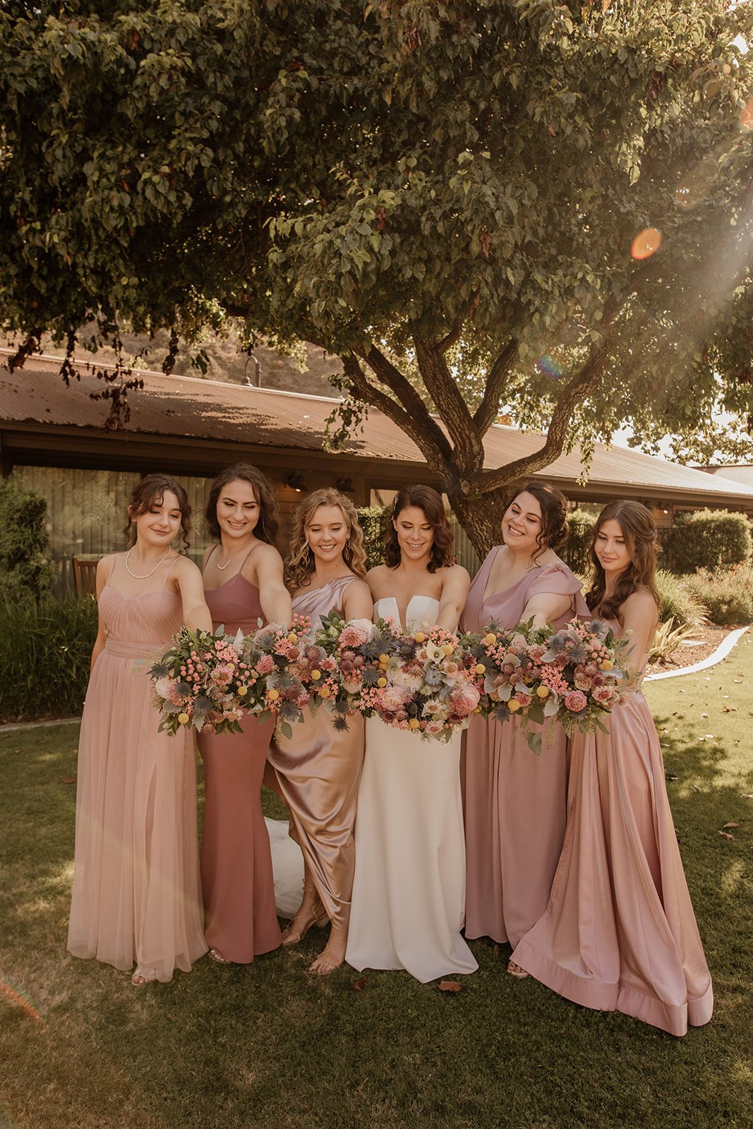 wedding day ceremony in laguna beach hosts beautiful bridal party wearing pinks, rose, and soft neutral bridesmaids dresses