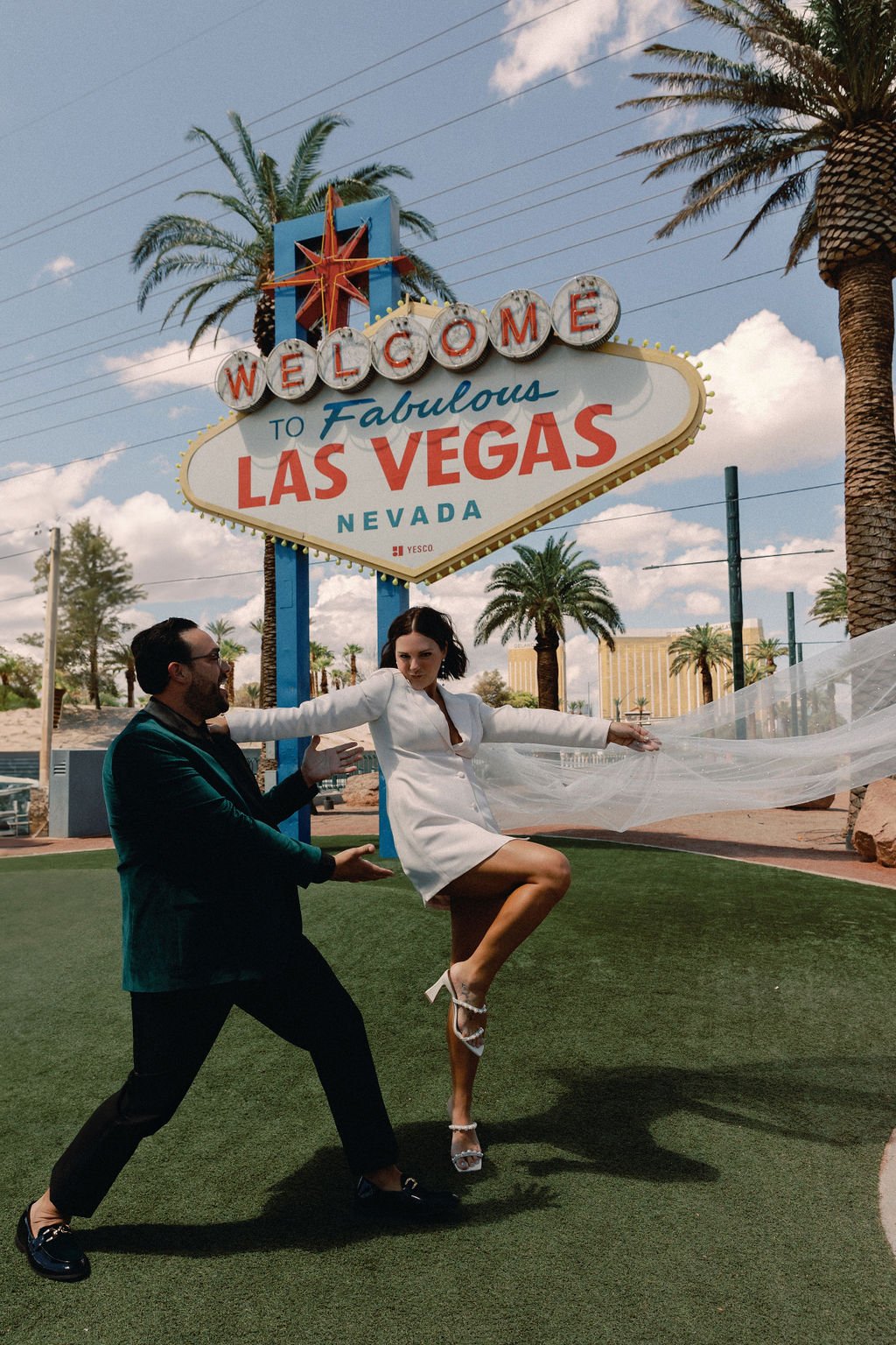 bride and groom take wedding day photos in front of the las vegas sign