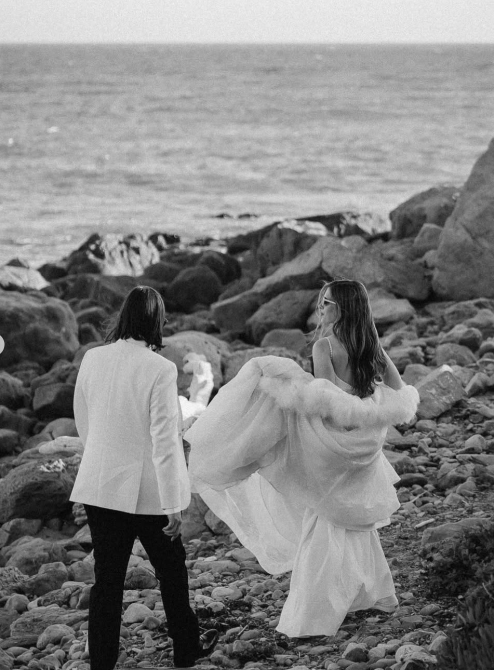 bride and groom walk off into the sunset after coastal malibu wedding