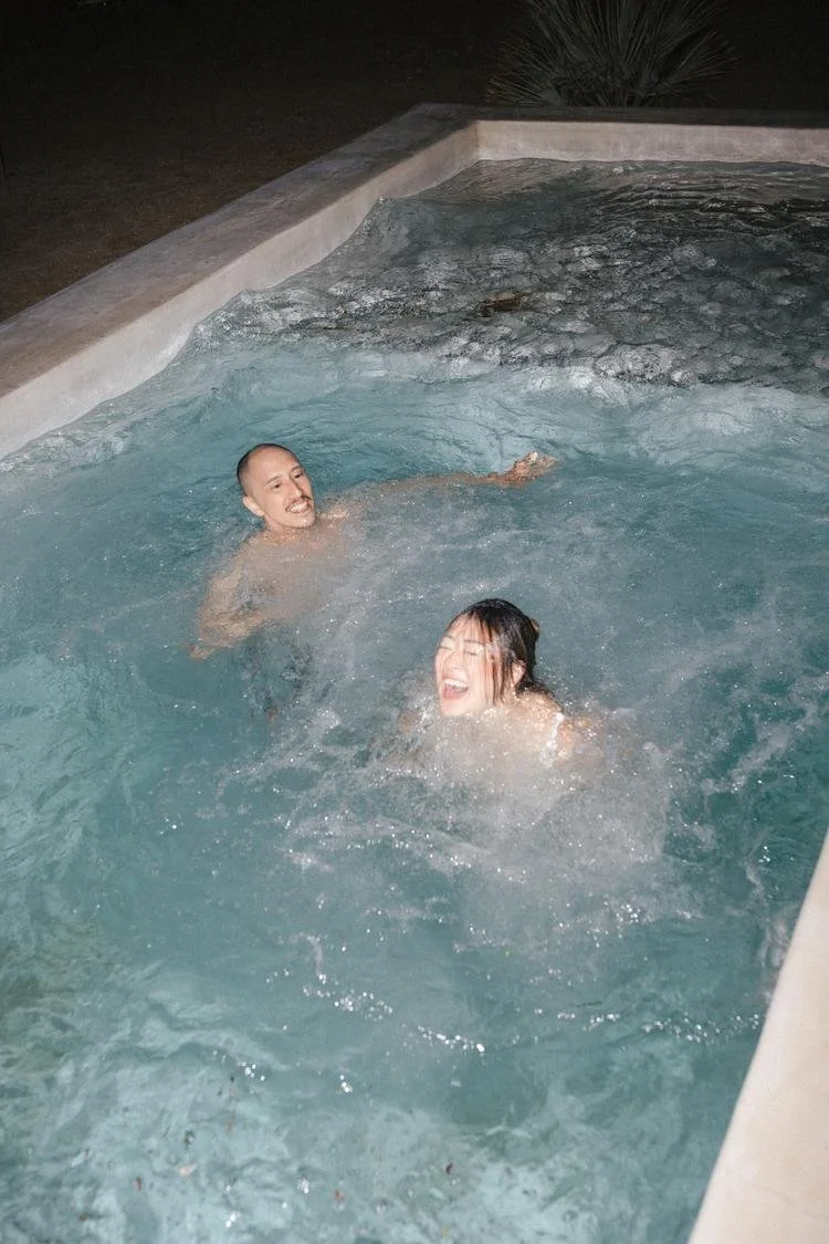 bride and groom jump in the pool at the end of their wedding day