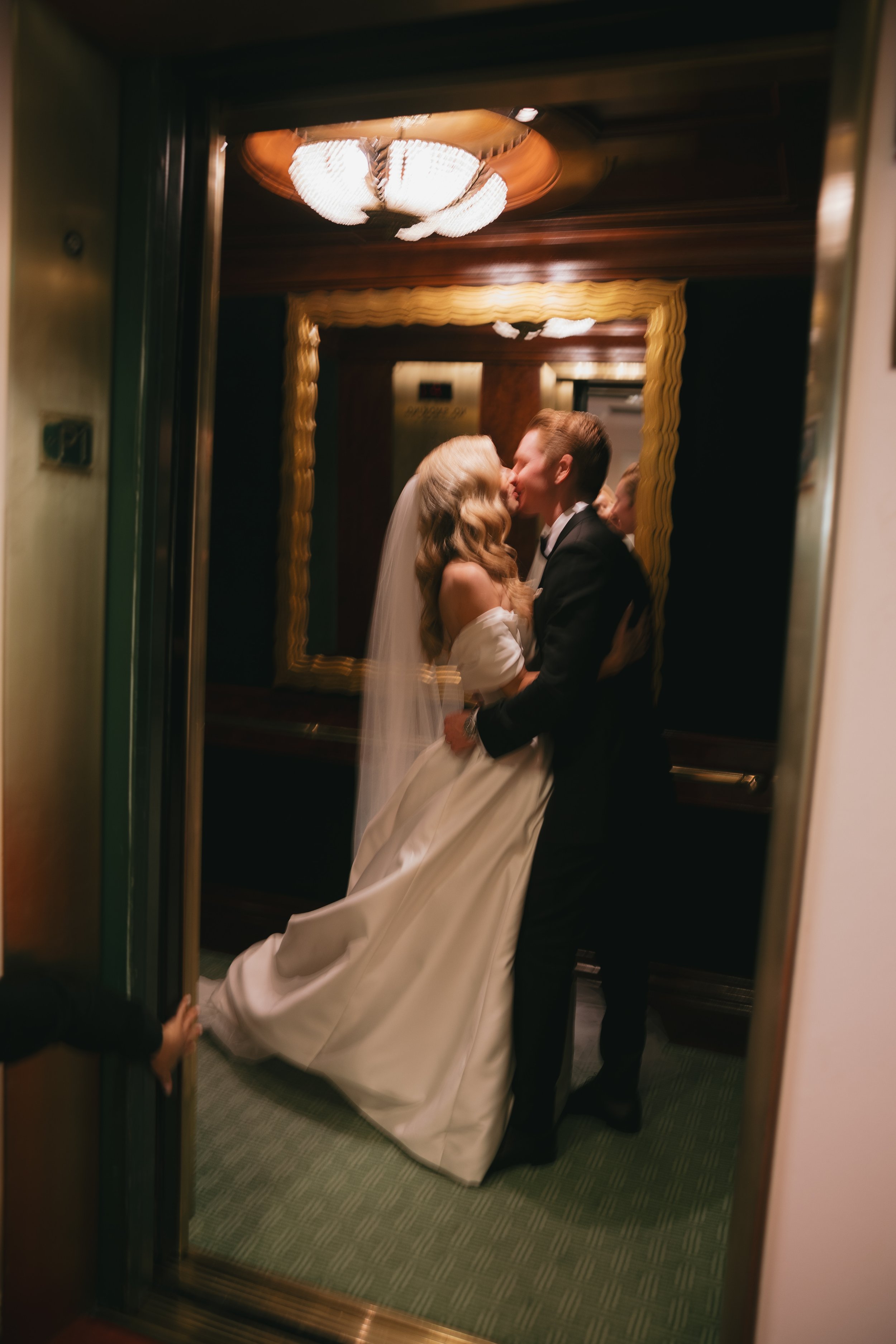 bride and groom share a kiss in the elevator of the beverly hills hotel