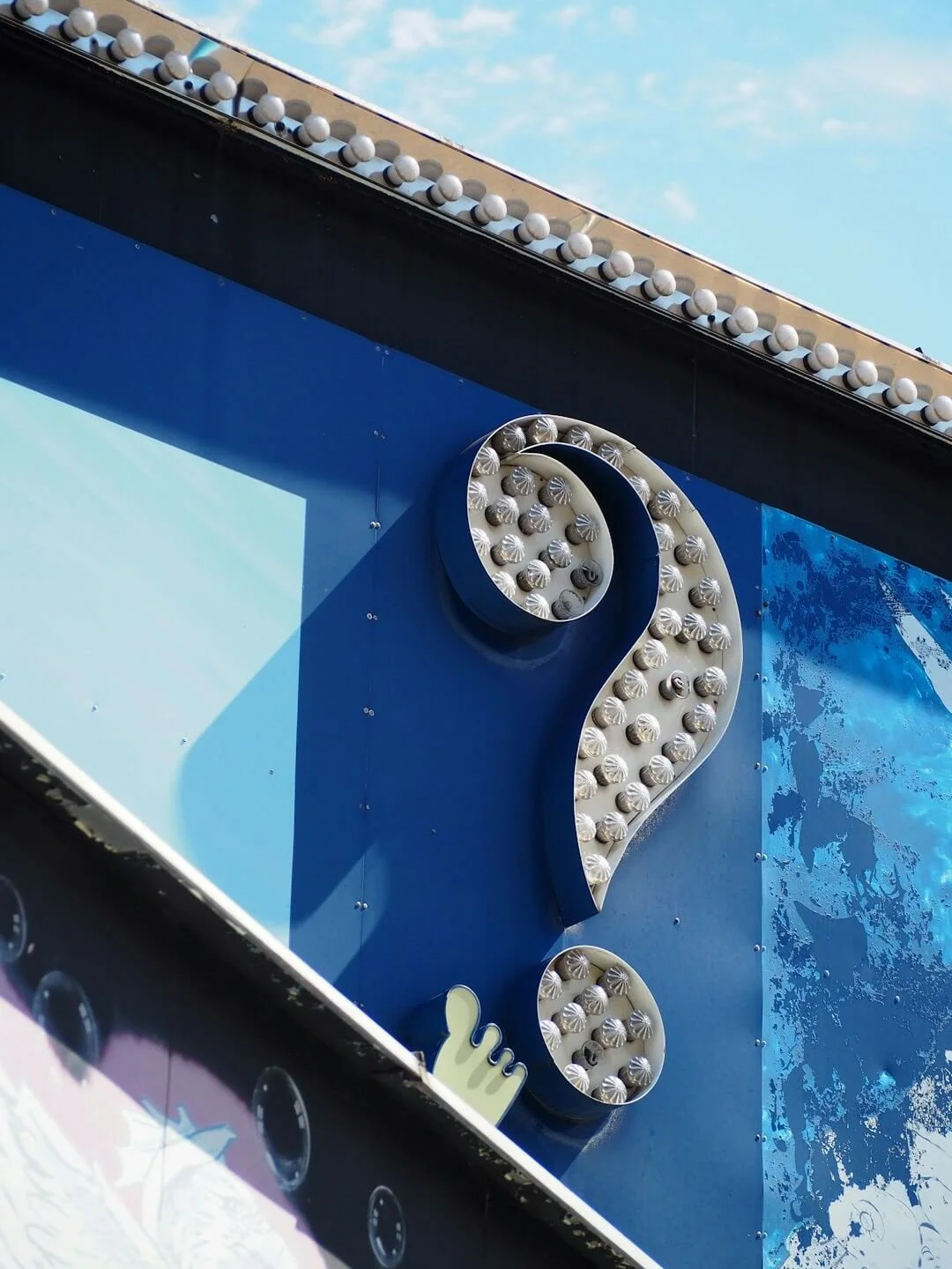 giant question mark sign on a blue wall