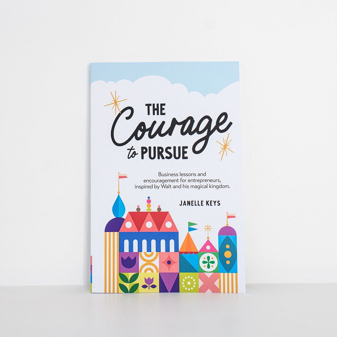 cover of book by Janelle Keys titled the courage to pursue business lessons and encouragement for entrepreneurs inspired by walt and his magical kingdom with colourful disney-esque castle on the cover