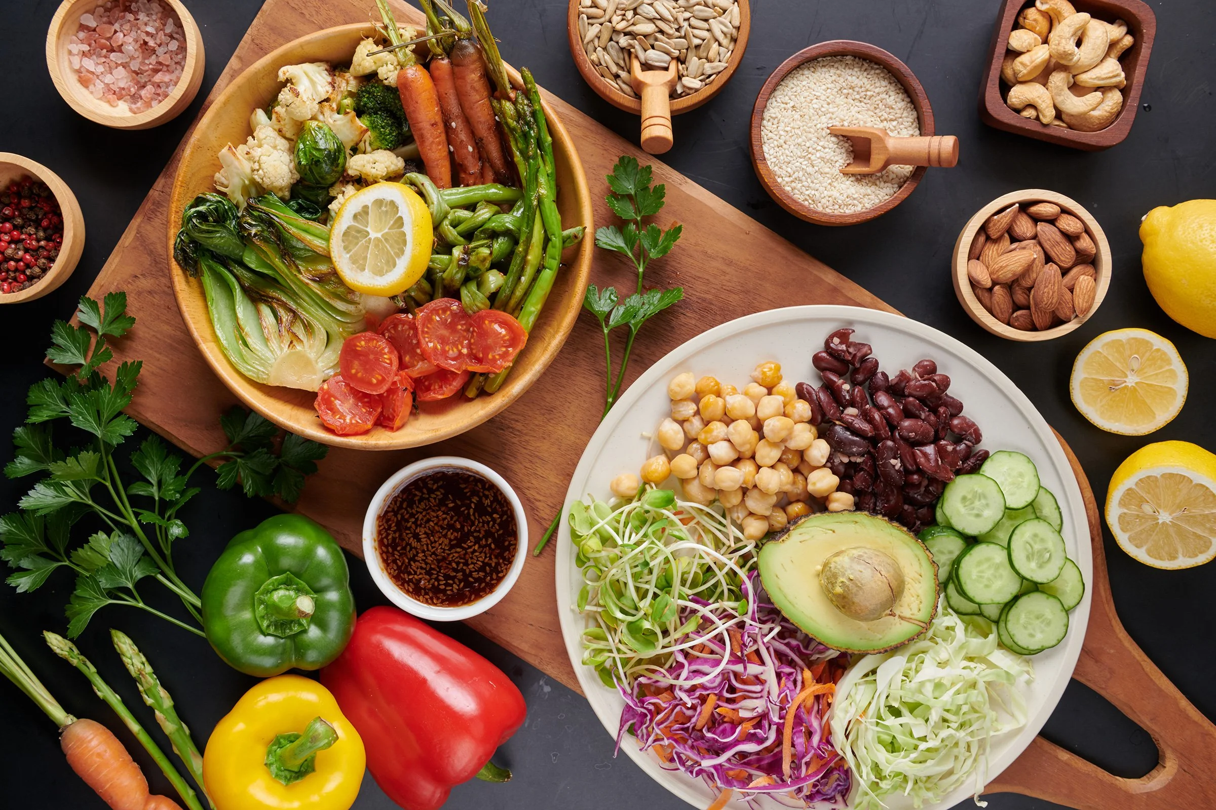 A colorful assortment of fresh vegetables, fruits, beans, nuts, and other whole foods arranged on a table.
