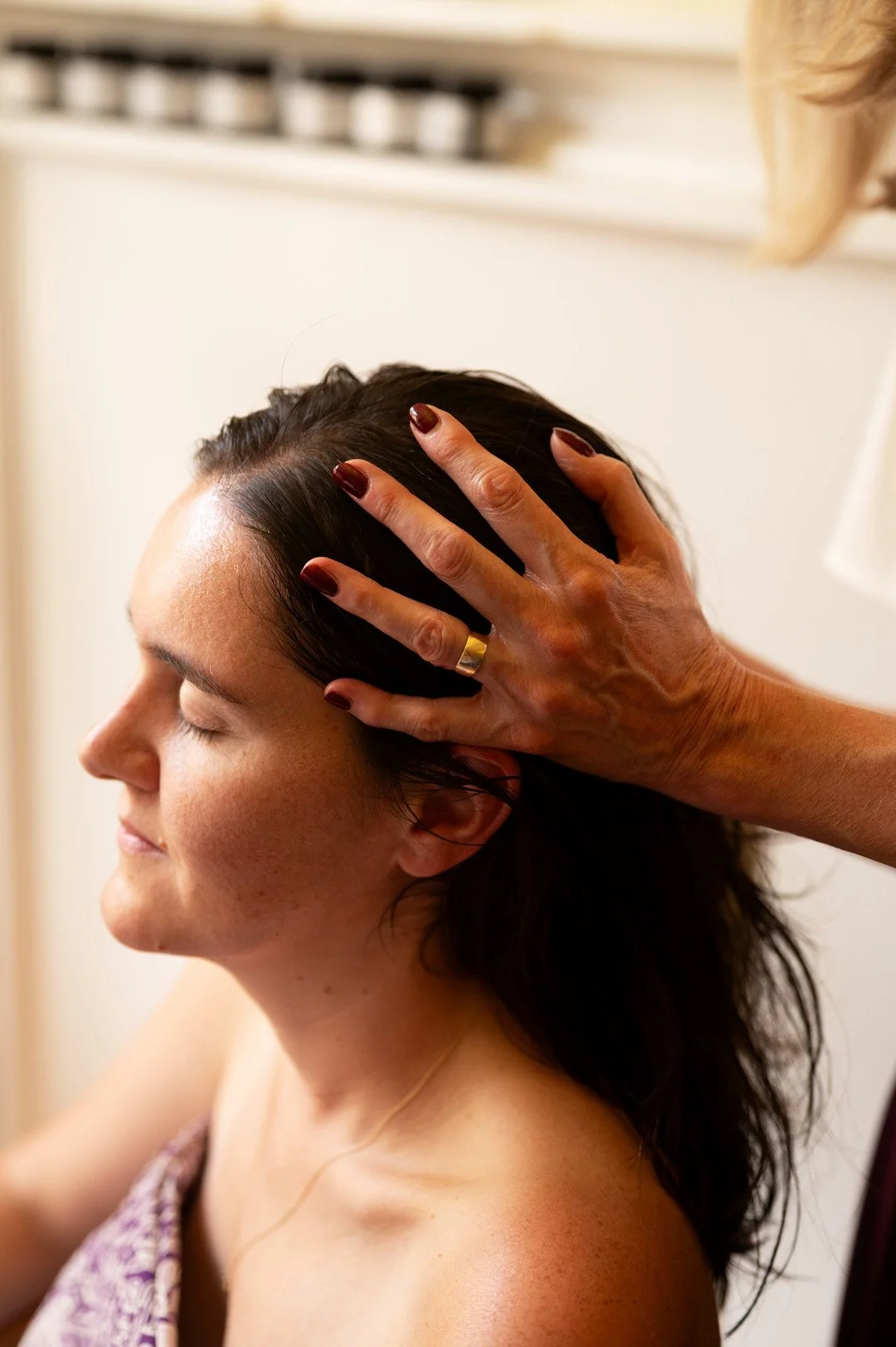 A woman receiving an indian head massage from Julie with eyes closed, in a relaxed state.