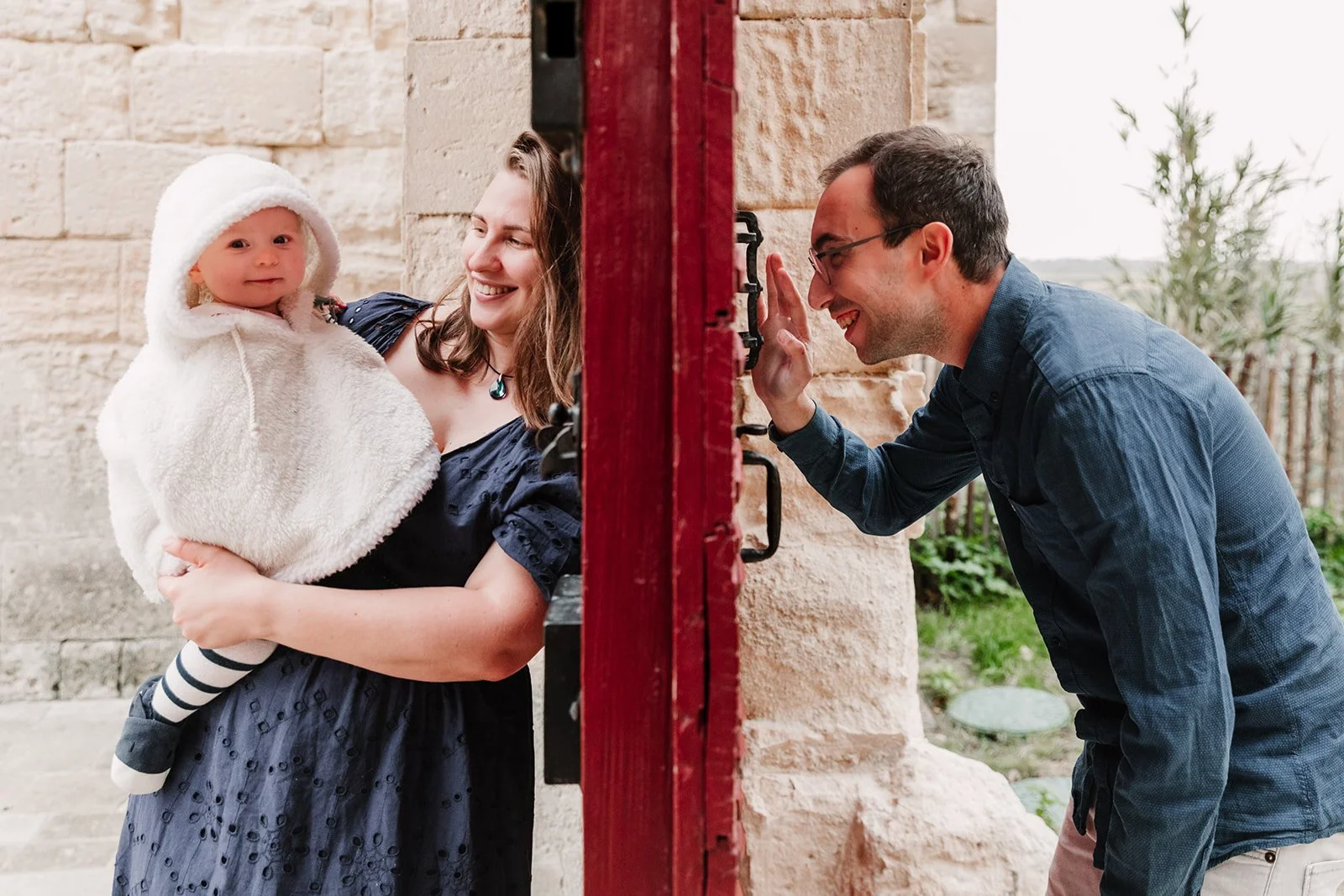 Papa regardant à travers une porte rouge maman et bebe