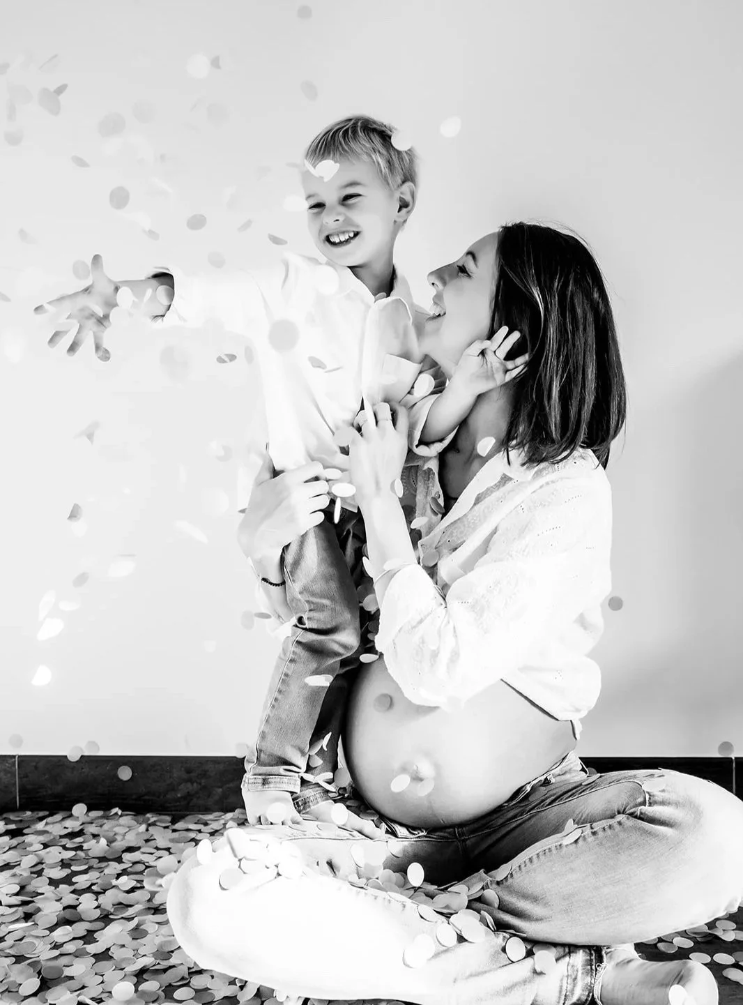 Femme enceinte et son petit garçon riant en lancant des confettis photo noir blanc