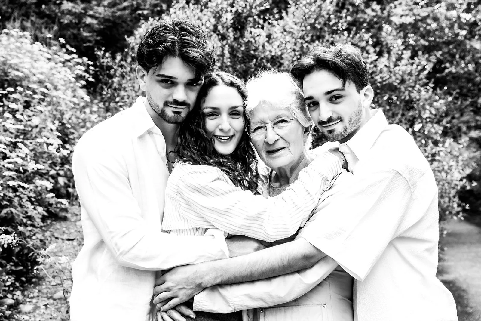 Jeune fille et jeunes garcons entourant leur grand mere dans jardin noir et blanc