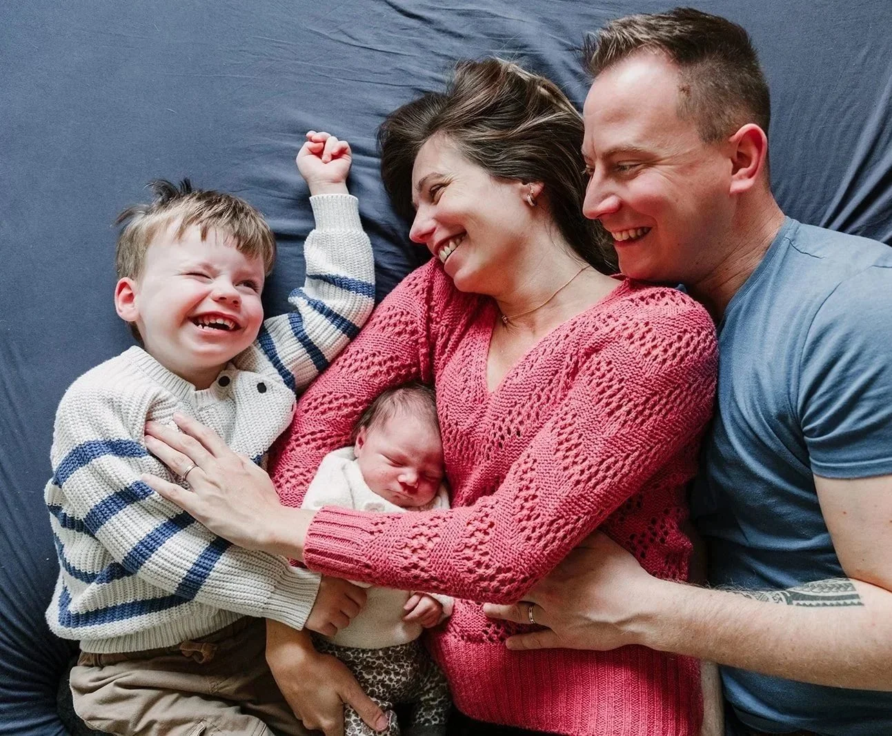 Famille riiant sur lit bleu petit garcon et bebe