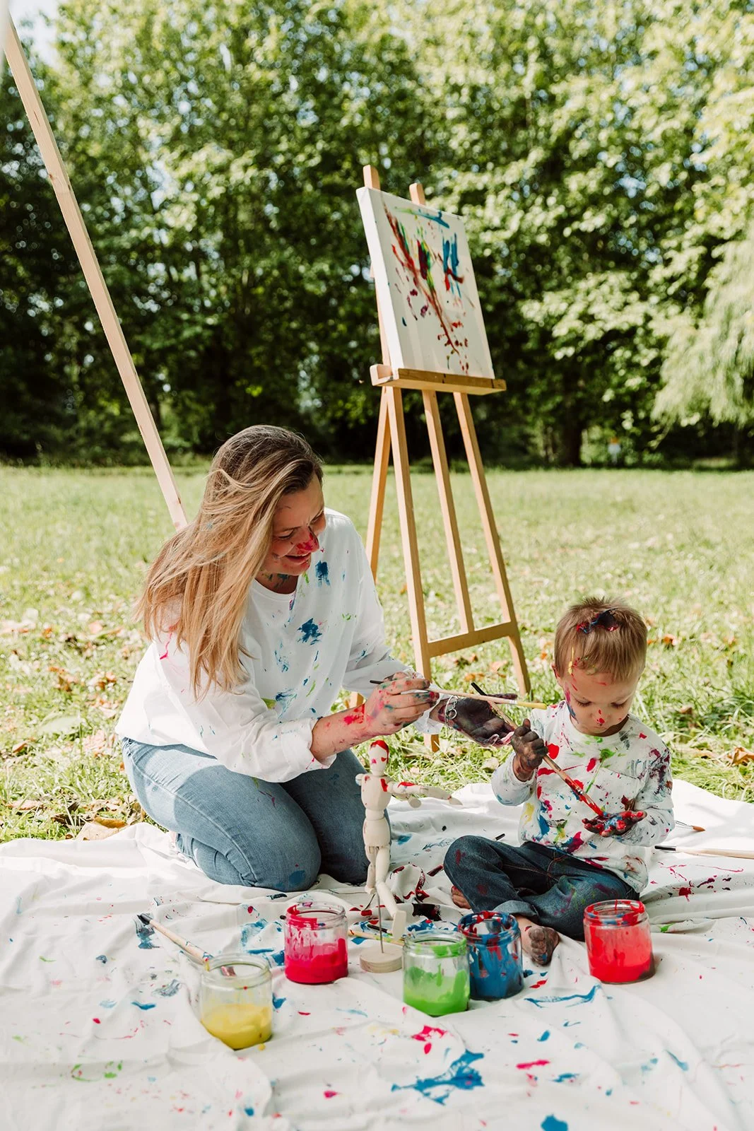 Maman et petit garcon dans l'herbe faisant un atelier peinture avec chevalet