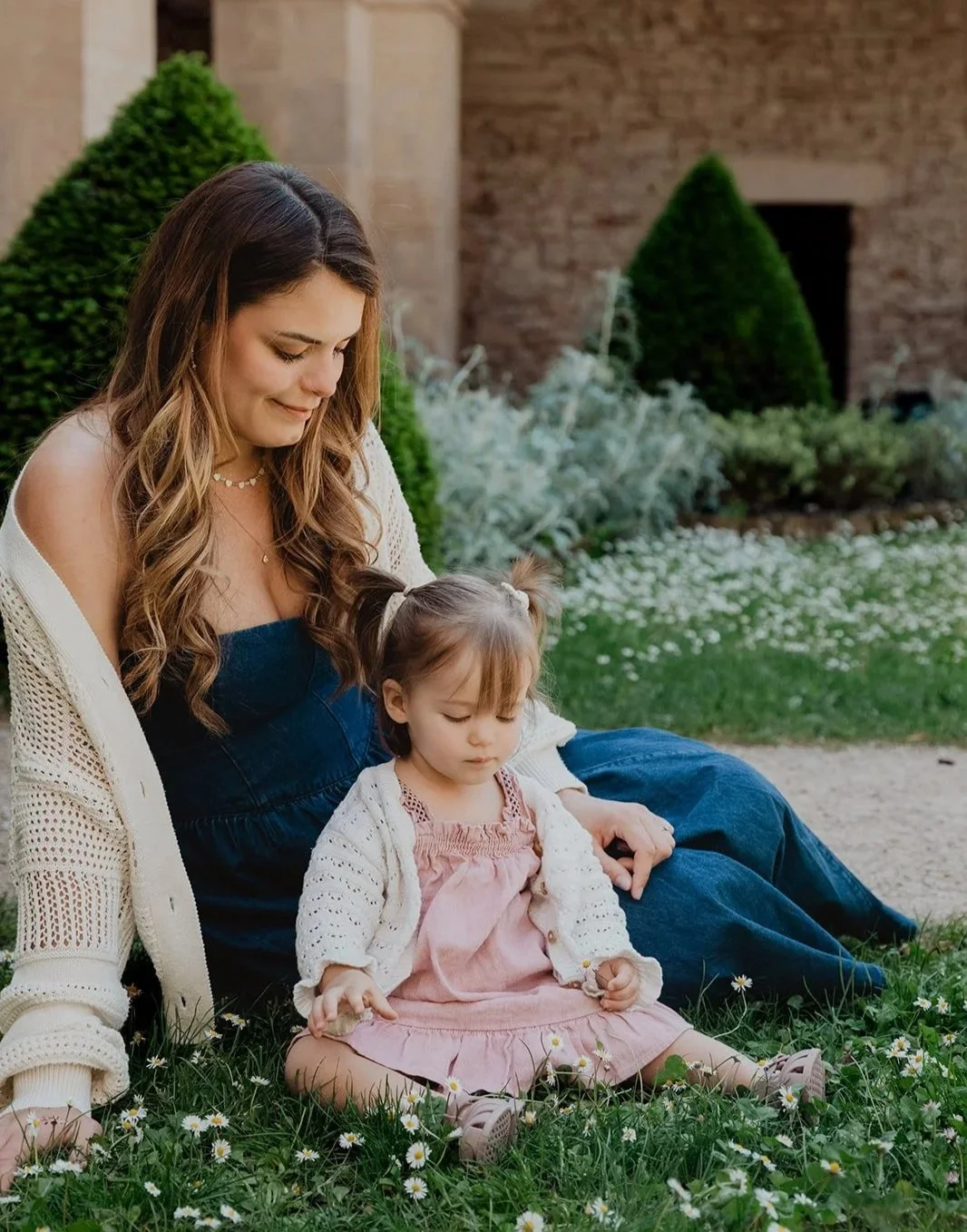 Femme assise dans l'herbe avec petite fille