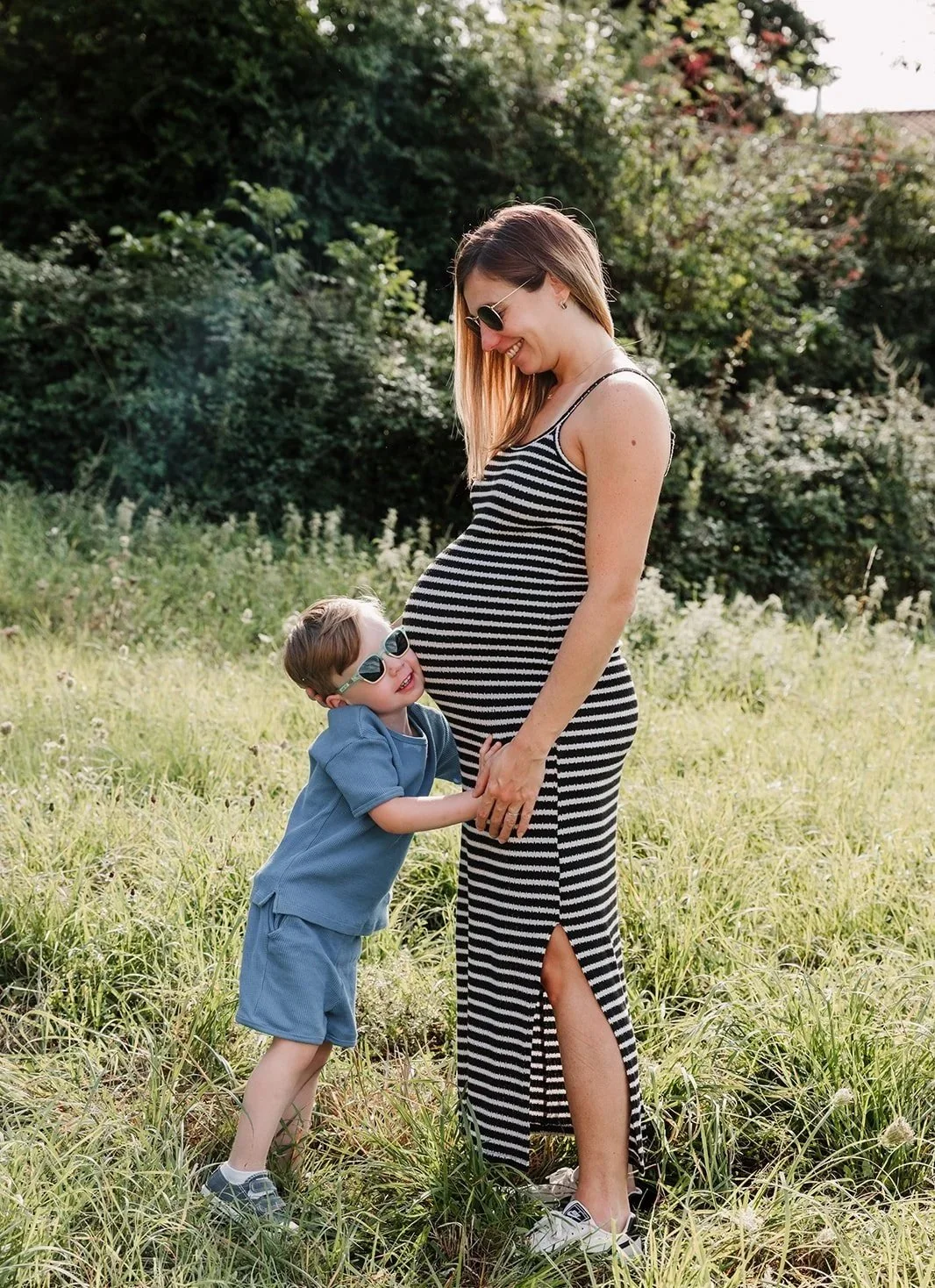 Petit garcon contre ventre grossesse maman dans l'herbe avec lunettes de soleil