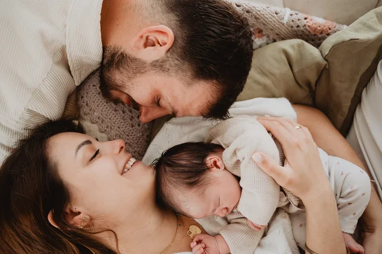 Parents allongés souriants avec leur bebe tons neutres