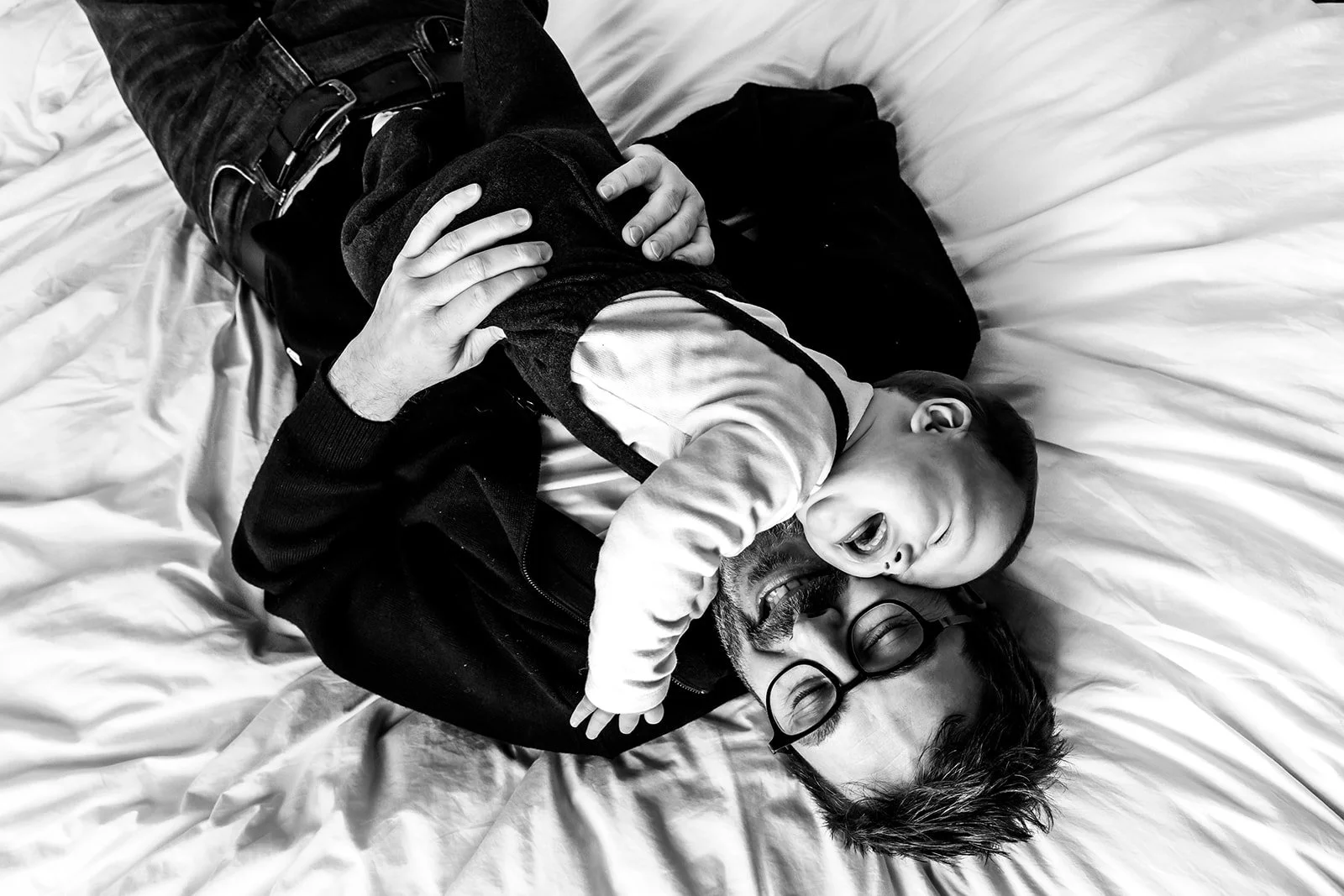 Papa et bébé sur lit eclatant de rire noir et blanc