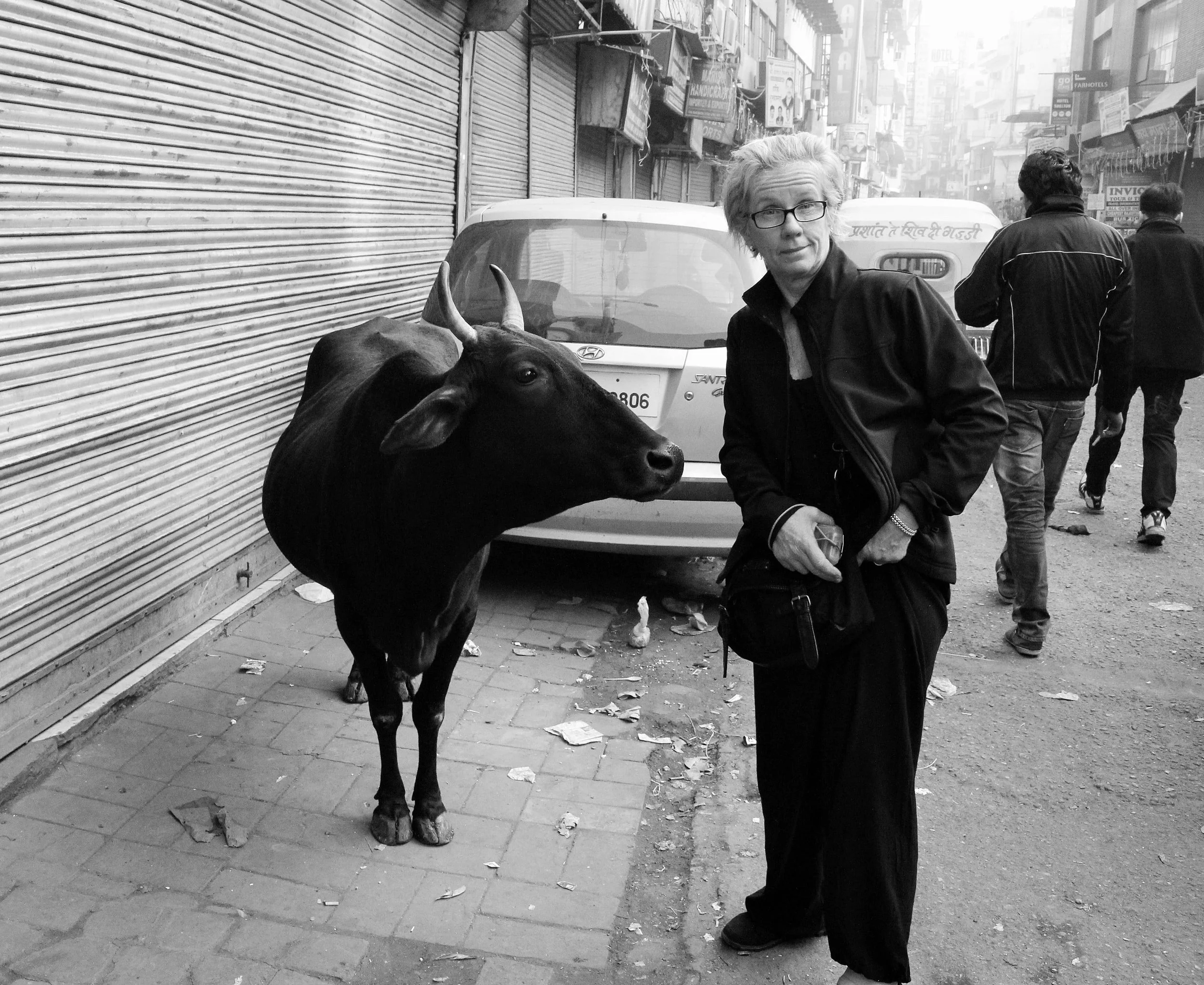 woman stands on road with cow