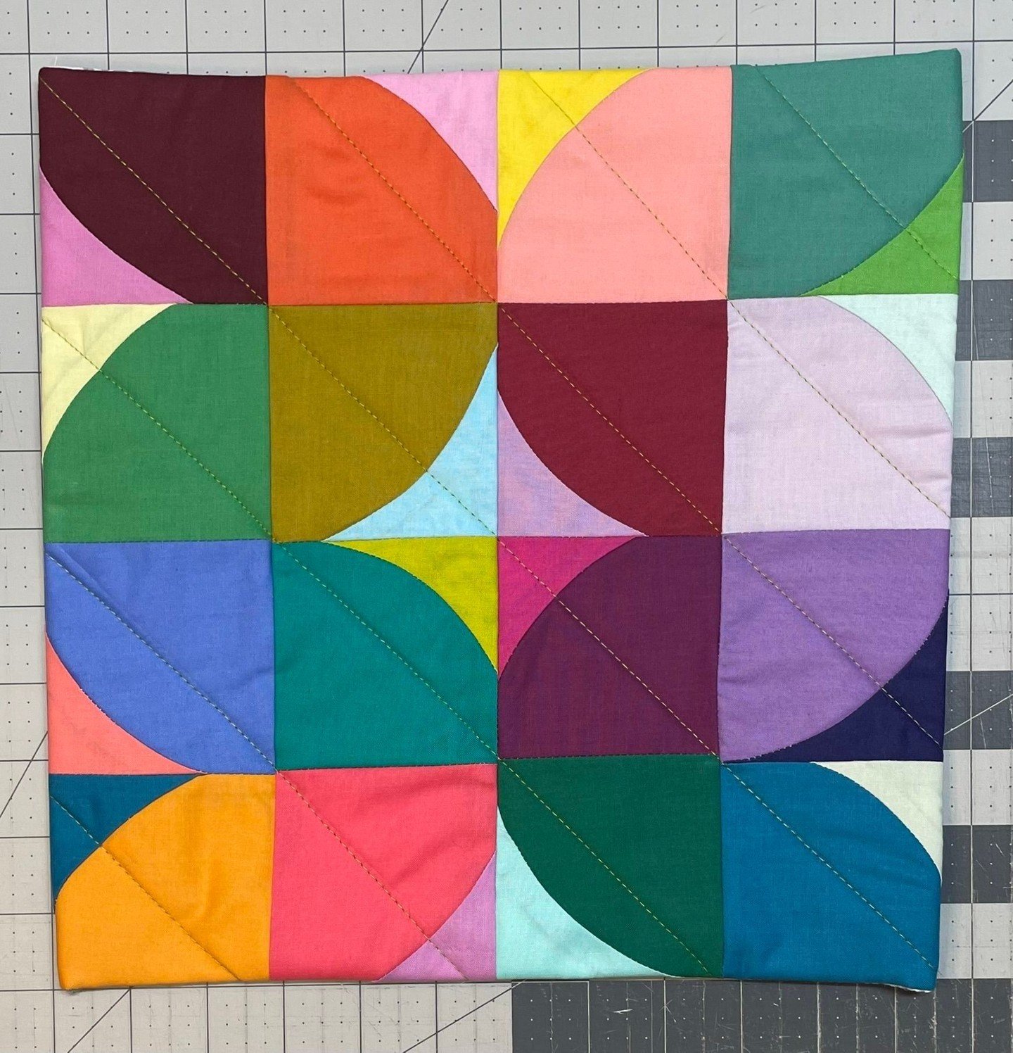 New work available!⁣
Modern, bright, quilted wall hanging features curved shapes in bold colors winding across this one of a kind, improvisationally designed mini quilt.  Straight, diagonal lines of stitching in citron provide contrast and add textur