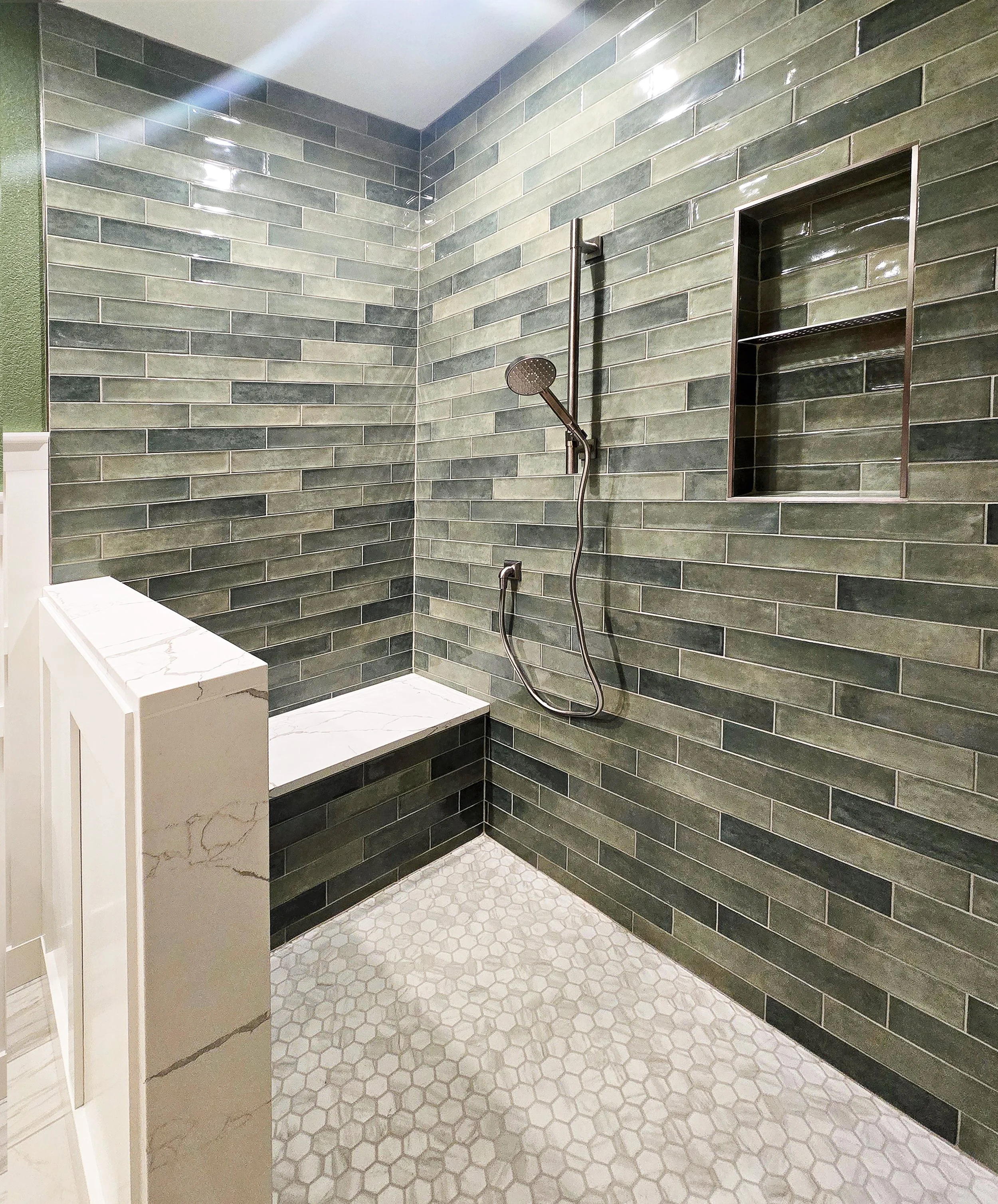 Luxury walk-in shower featuring a custom-built shower pan with a modern linear drain and a built-in bench topped with matching quartz in Merrimac, WI.