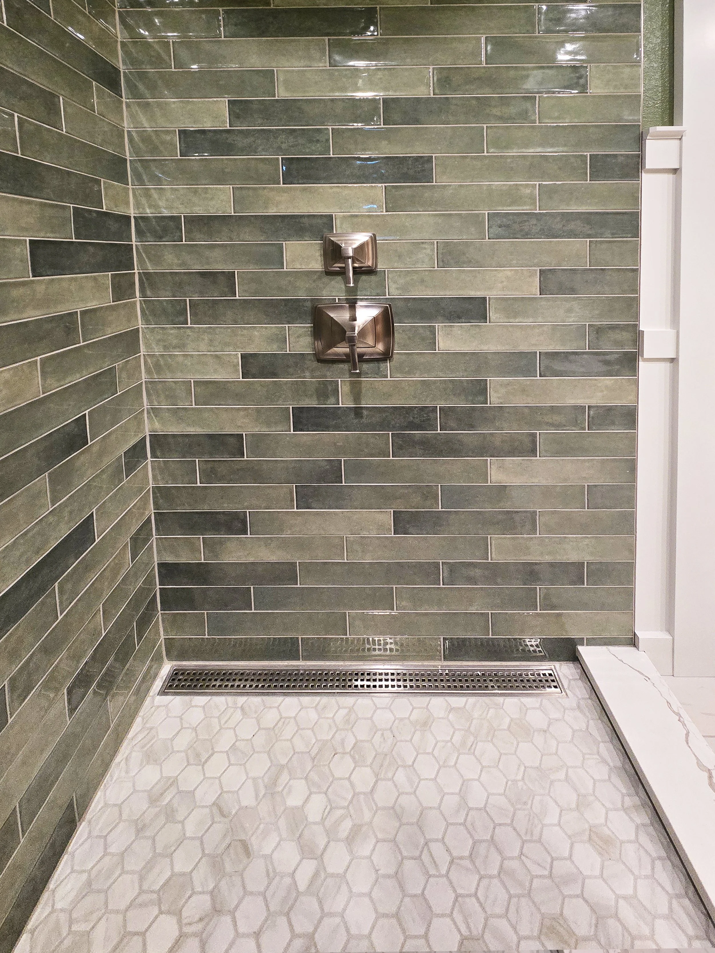Luxury walk-in shower featuring a custom-built shower pan in Merrimac, WI with a modern linear drain and a built-in bench topped with matching quartz.