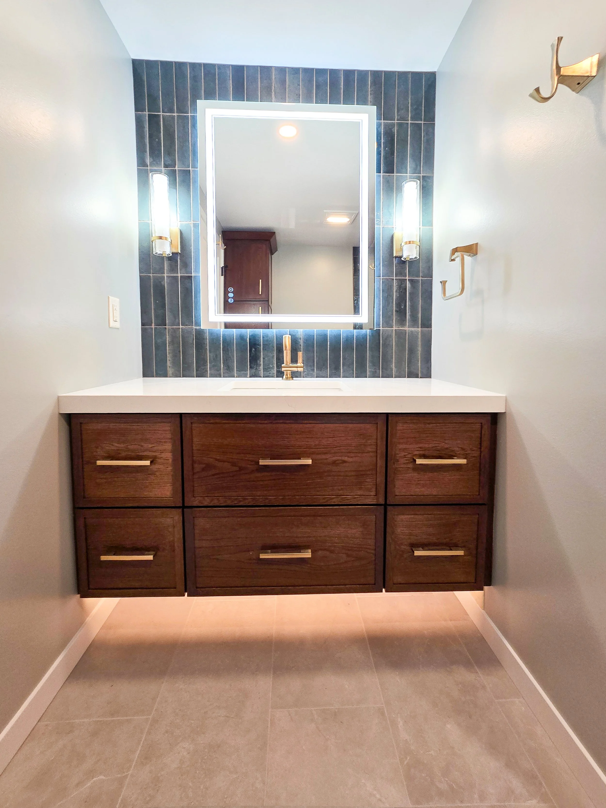 Modern bathroom with hand-painted tile backsplash, backlit mirror, and floating vanity.