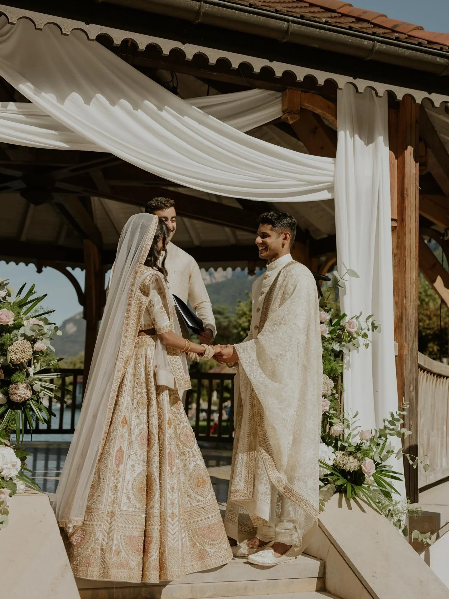 Alisha &amp; Faraaz
An intimate joyful lakeside ceremony unfolds on the edge of Lac d&rsquo;Annecy, featuring beautifully draped fabric in soft, flowing layers. Indian-Western fusion flowers in dusty pink tones mingle with rustic bronze accents, crea
