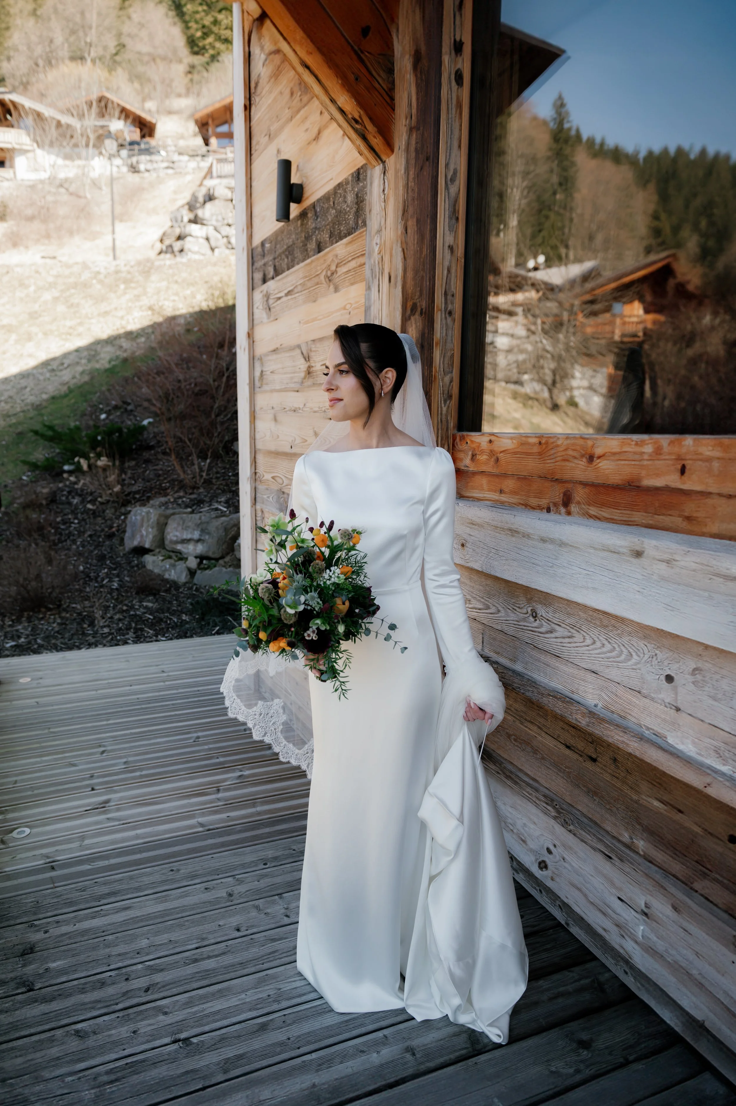 Dainty rustic wildflower style bridal bouquet with colorful blooms, beside an alpine chalet, capturing cozy wedding charm and mountain beauty.
