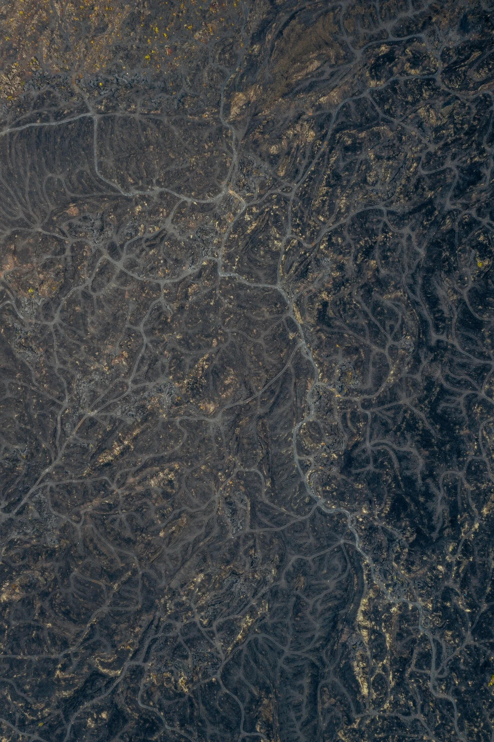 Satellite image of dark land with a network of winding roads and scattered lights, possibly an urban or suburban area at night.