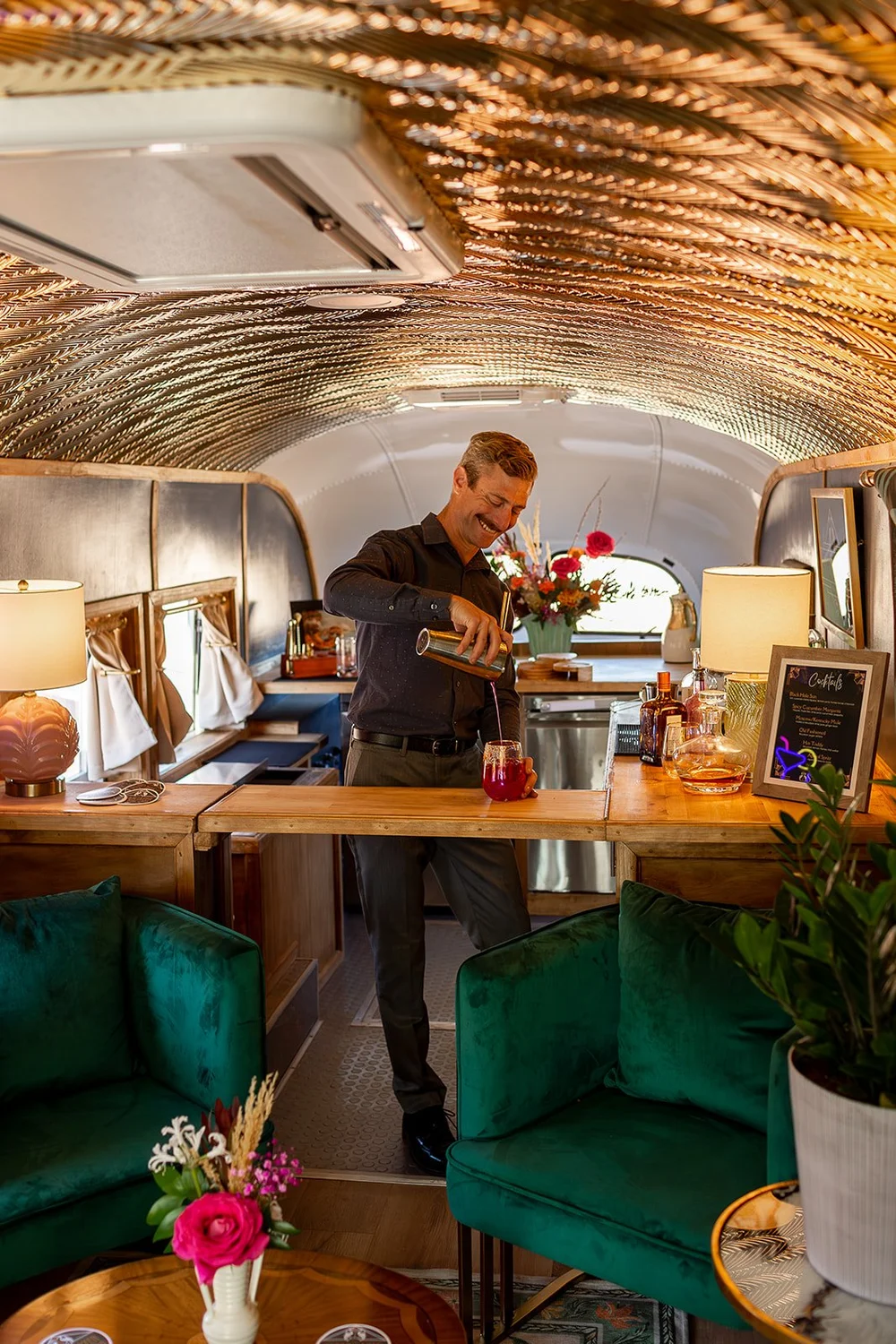 A bartender pouring a craft cocktail inside Regina's gold-ceilinged lounge