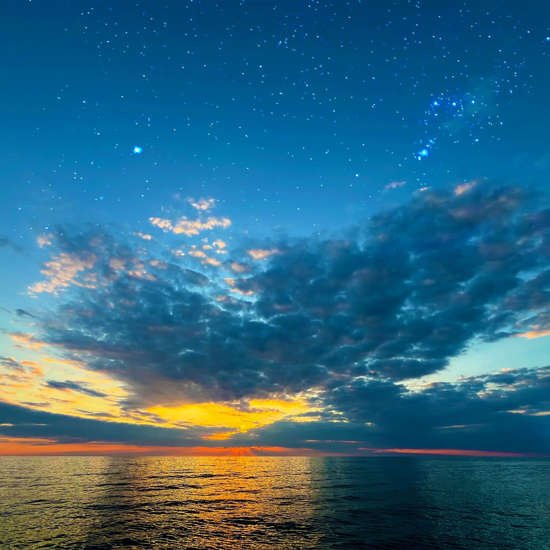 Clouds, sunset, stars shining and glowing over lake