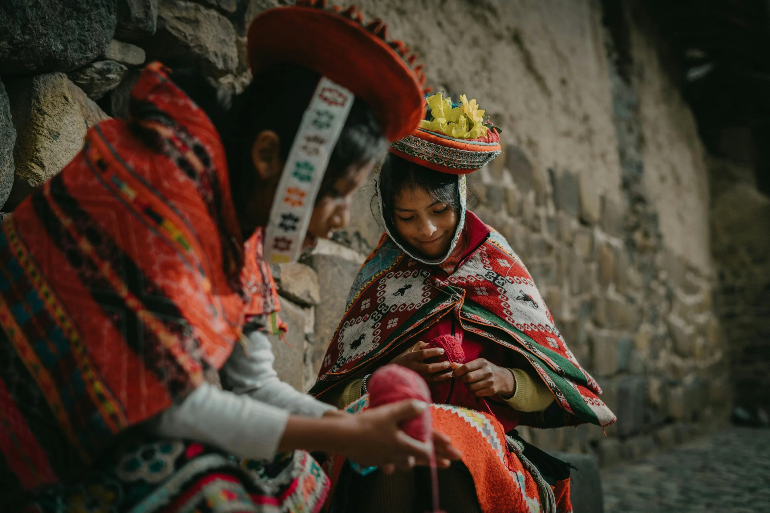 Two Peruvian women hand weaving outside
