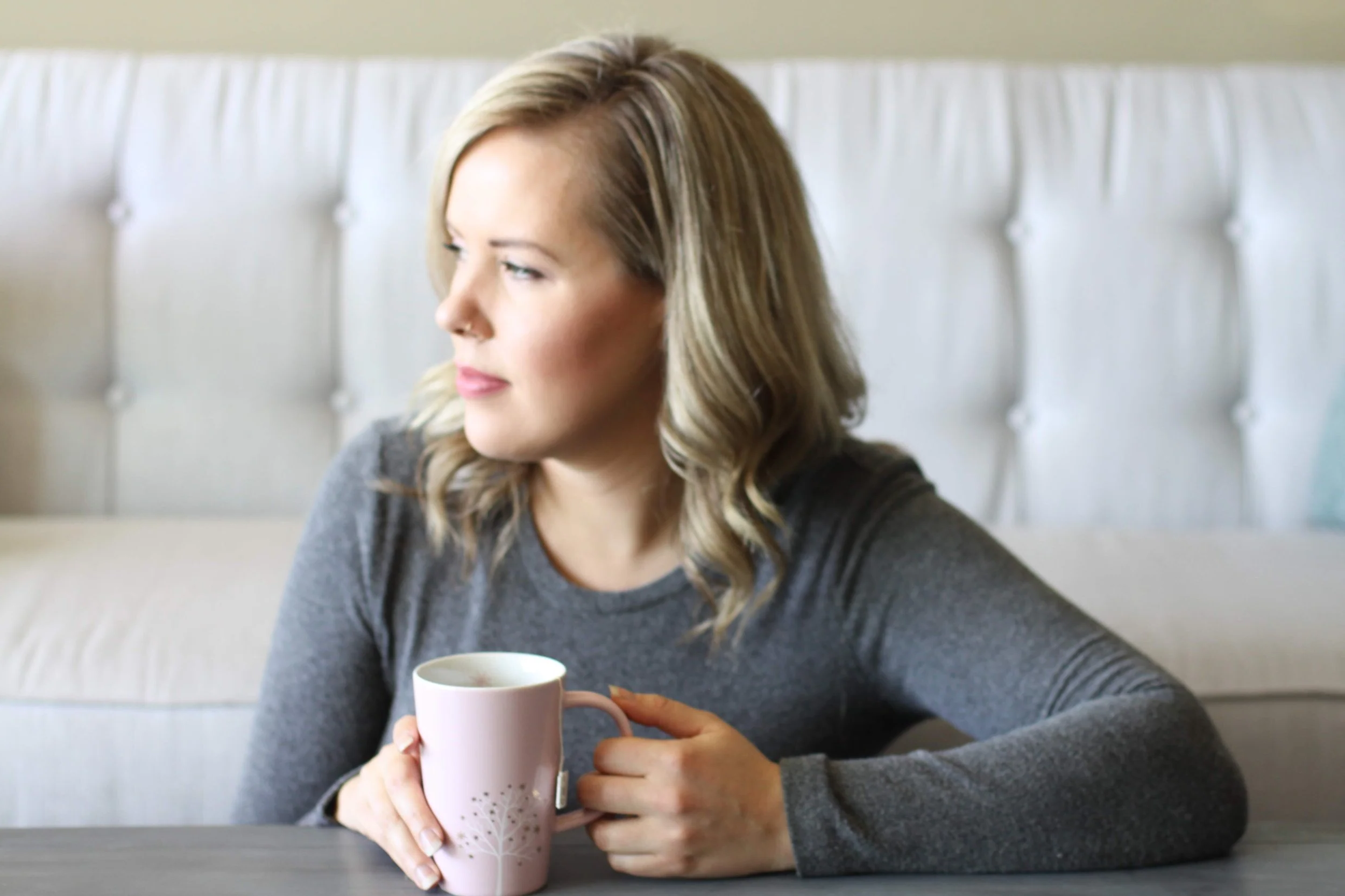 A woman holding a cup of tea and looking off to the side
