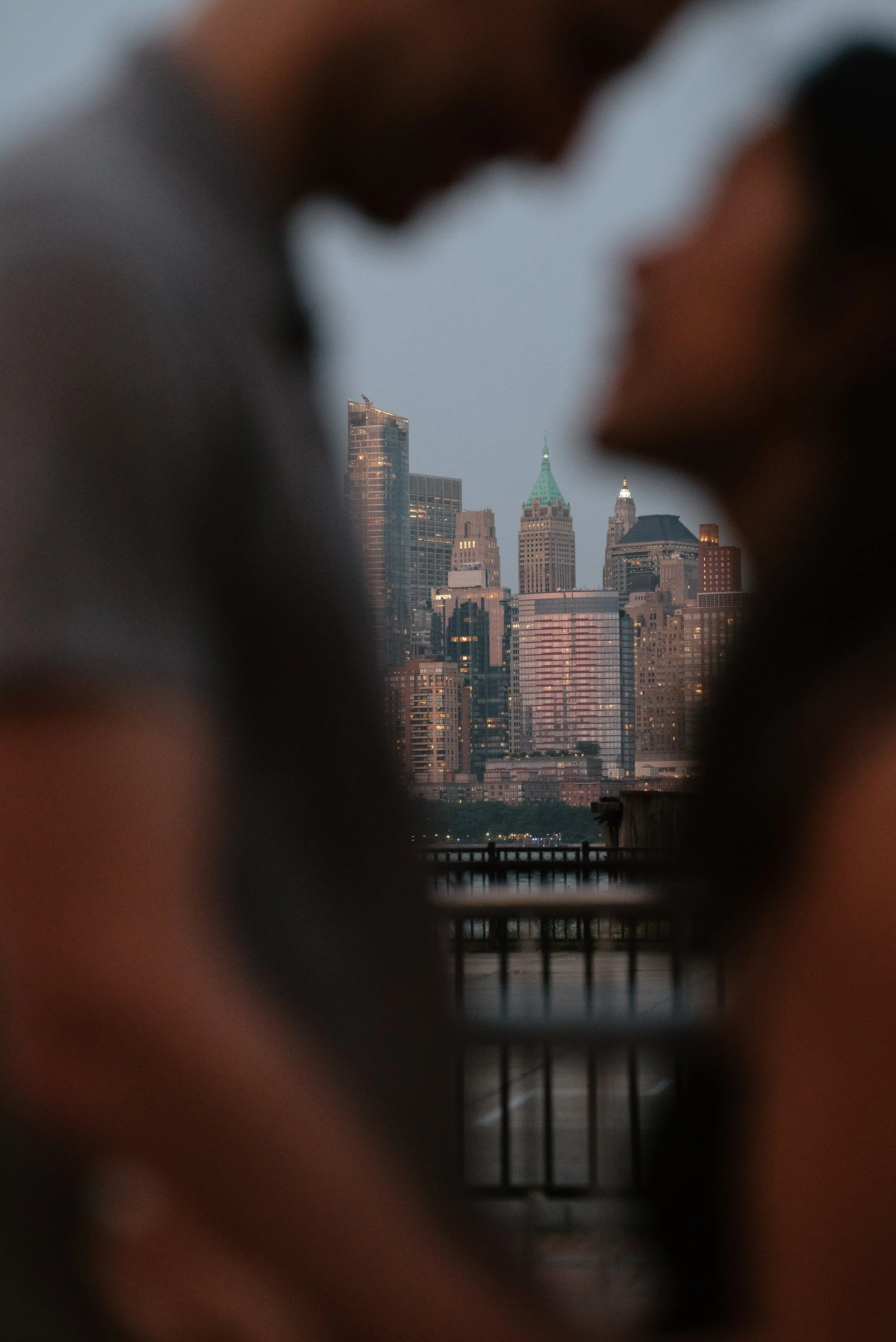 A couple kissing with a view of the New York City skyline through their silhouette.