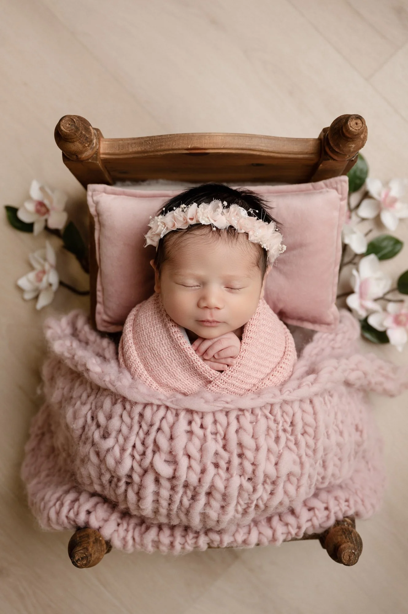 image of newborn baby girl swaddled in pink in tiny newborn bed