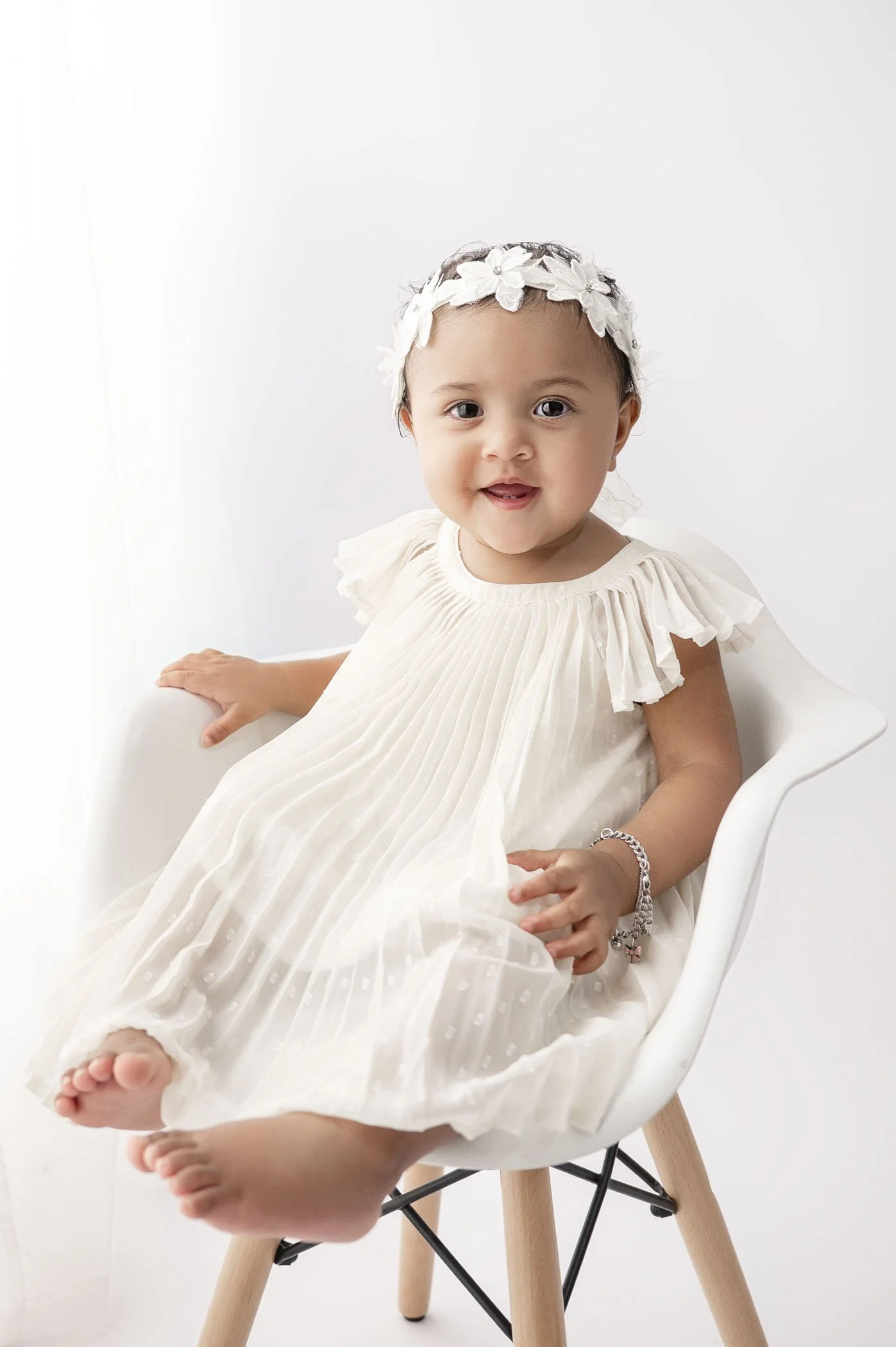one year old wearing white dress on all white background during houston cake smash session