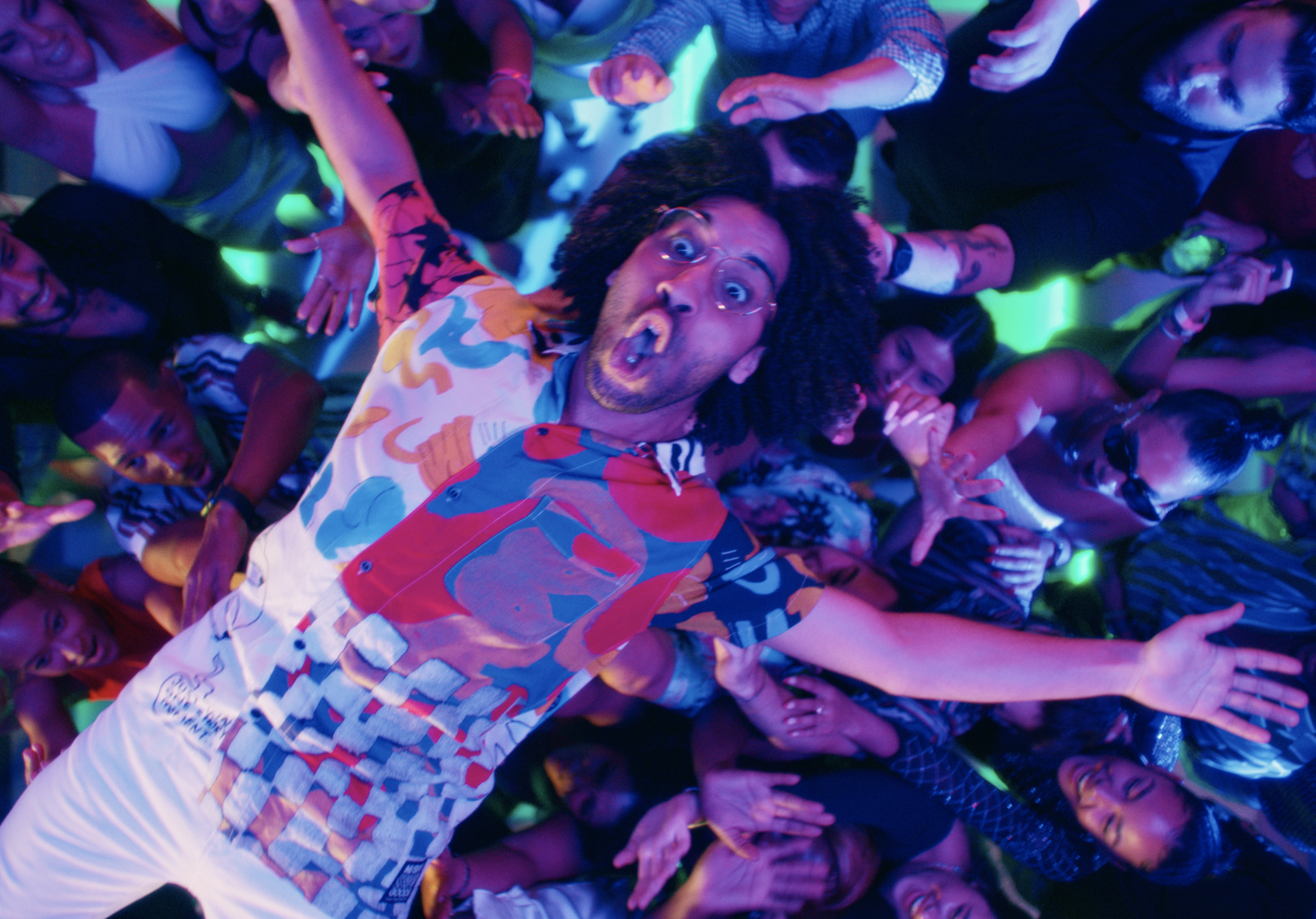 Person crowd surfing at a lively party with arms outstretched, surrounded by cheerful people.