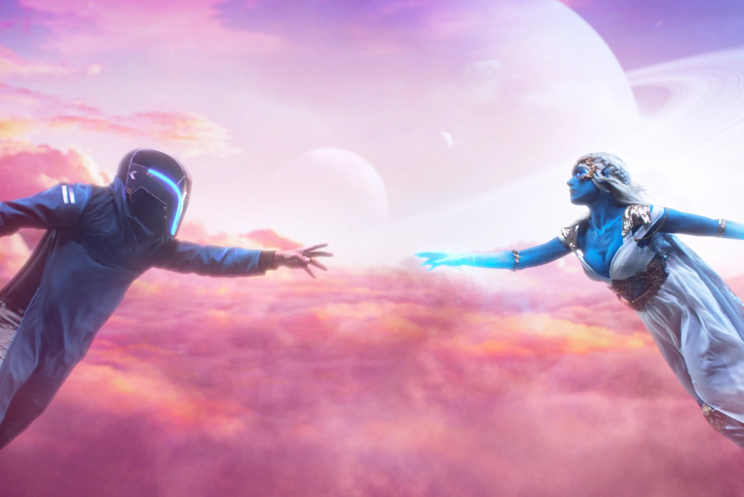 A futuristic scene with a person wearing a helmet reaching out to a blue-skinned woman in a white gown, set against a colorful, cloud-filled alien landscape with planets in the background.