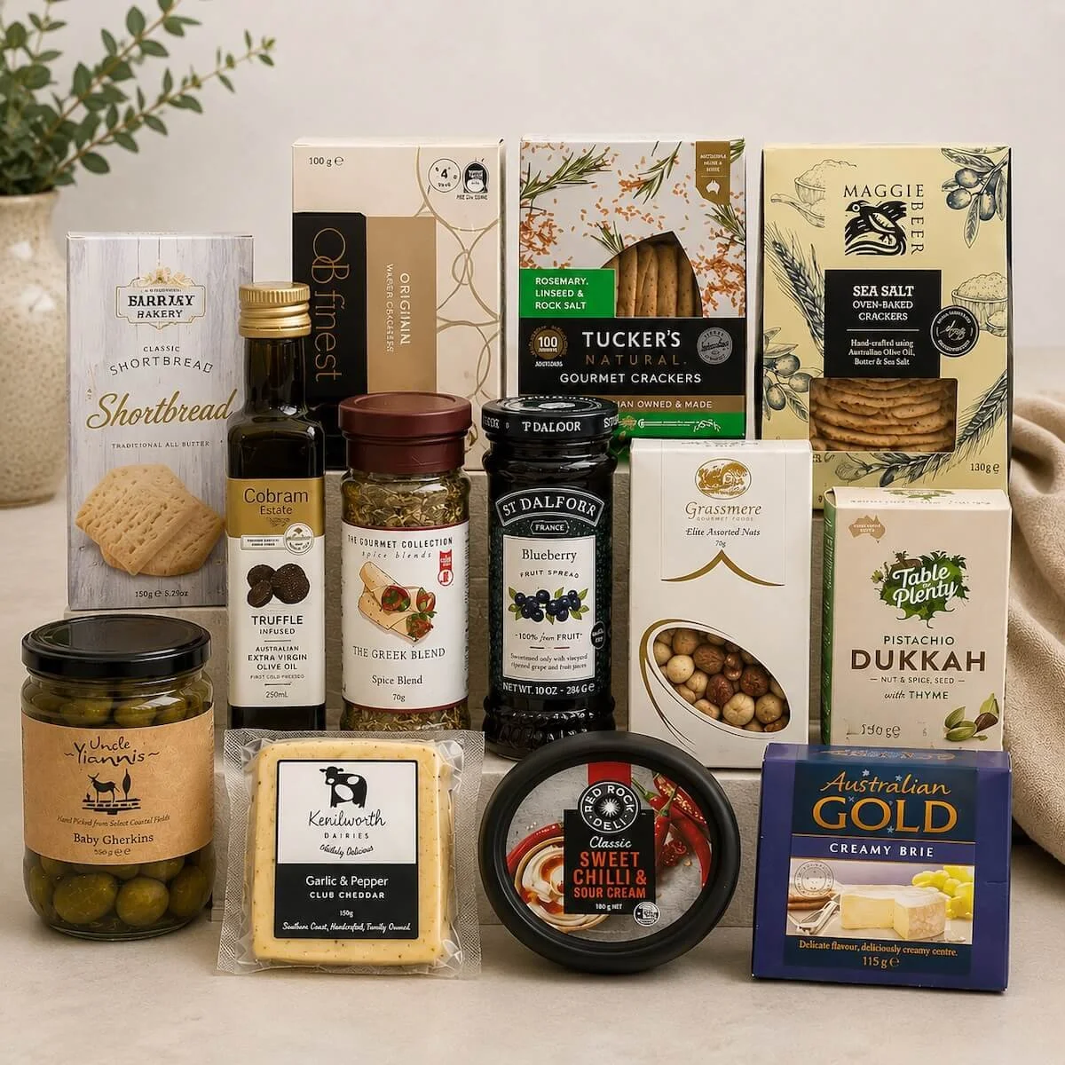Gourmet indlugence hamper items, cheeses, crackers, and a large assortment of sweet and savoury foods arranged in a gift tray.