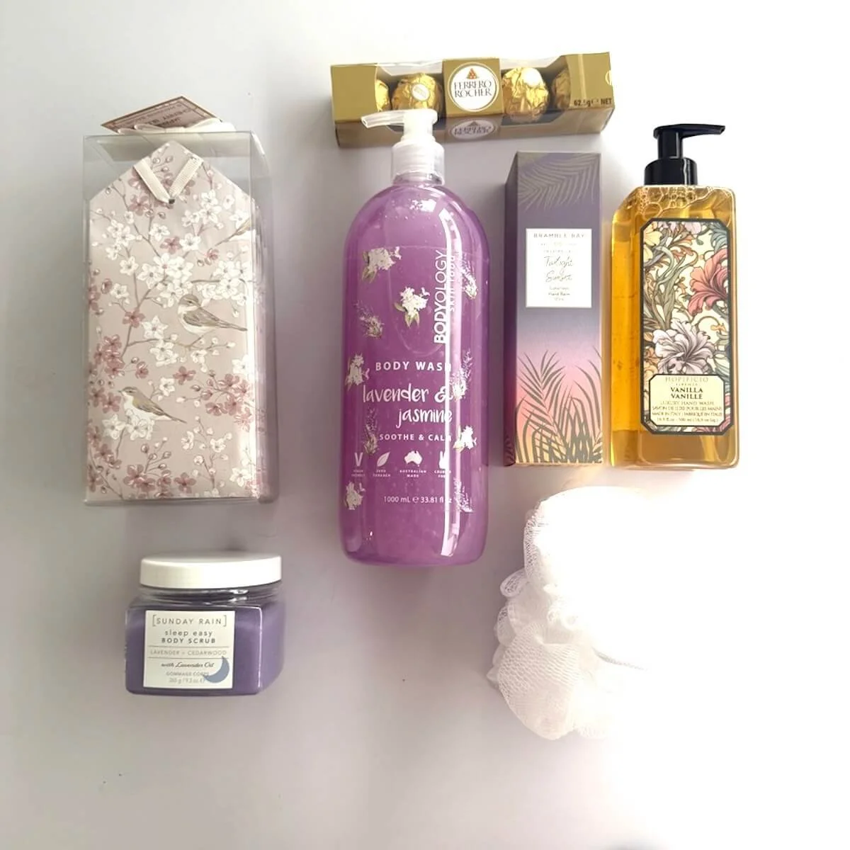 Luxury pamper hamper products including body wash, hand cream, vanilla hand wash, body scrub, Ferrero Rocher chocolates and sachets.