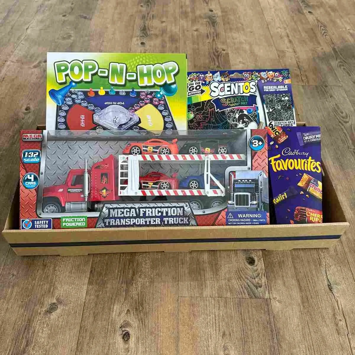Boys Gift hamper with a Transporter Truck toy, Pop-n-hop game, Scratch art kit and Favourites chocolates in a gift tray.