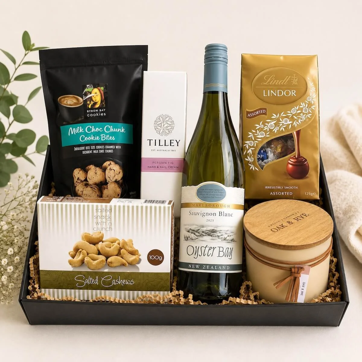 Gift tray with lindt chocolates, byron bay cookies, cashew nuts, a two wick candle and 700 ml bottle of wine.