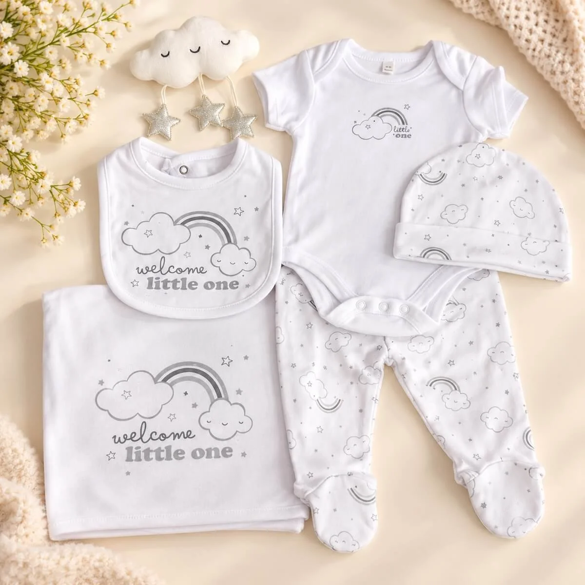 Newborn baby clothing set with white bodysuit, footed pants, matching hat, bib, blanket and cloud toy with silver stars.